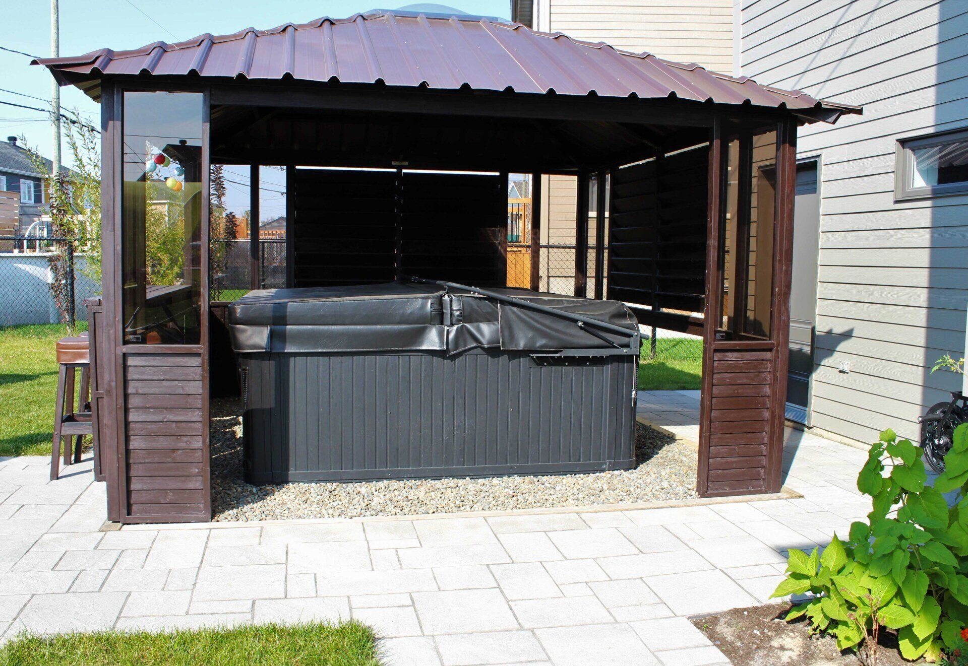 Un bain à remous est installé sous un belvédère dans une cour arrière.