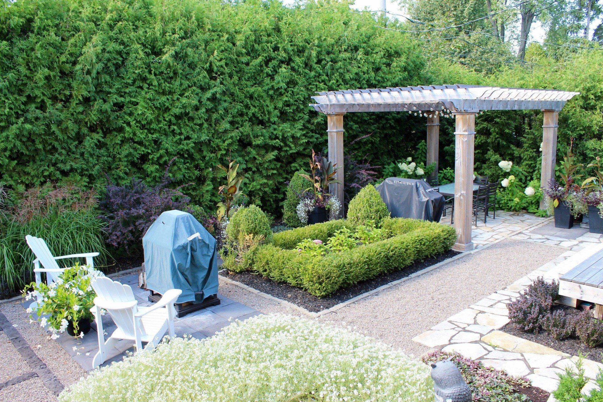 Une cour arrière avec un barbecue, des chaises et une pergola.
