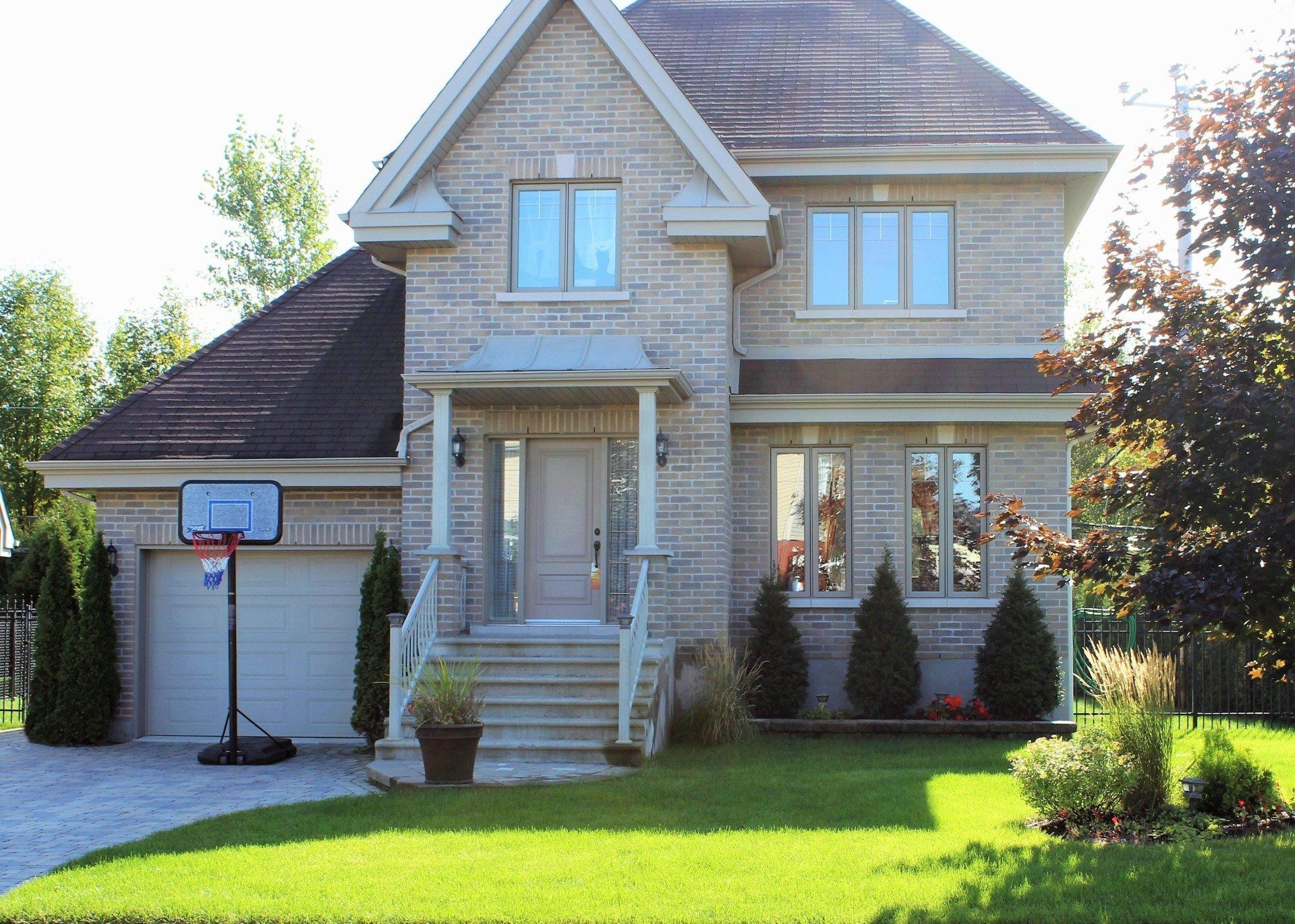 Une grande maison en briques avec un panier de basket devant