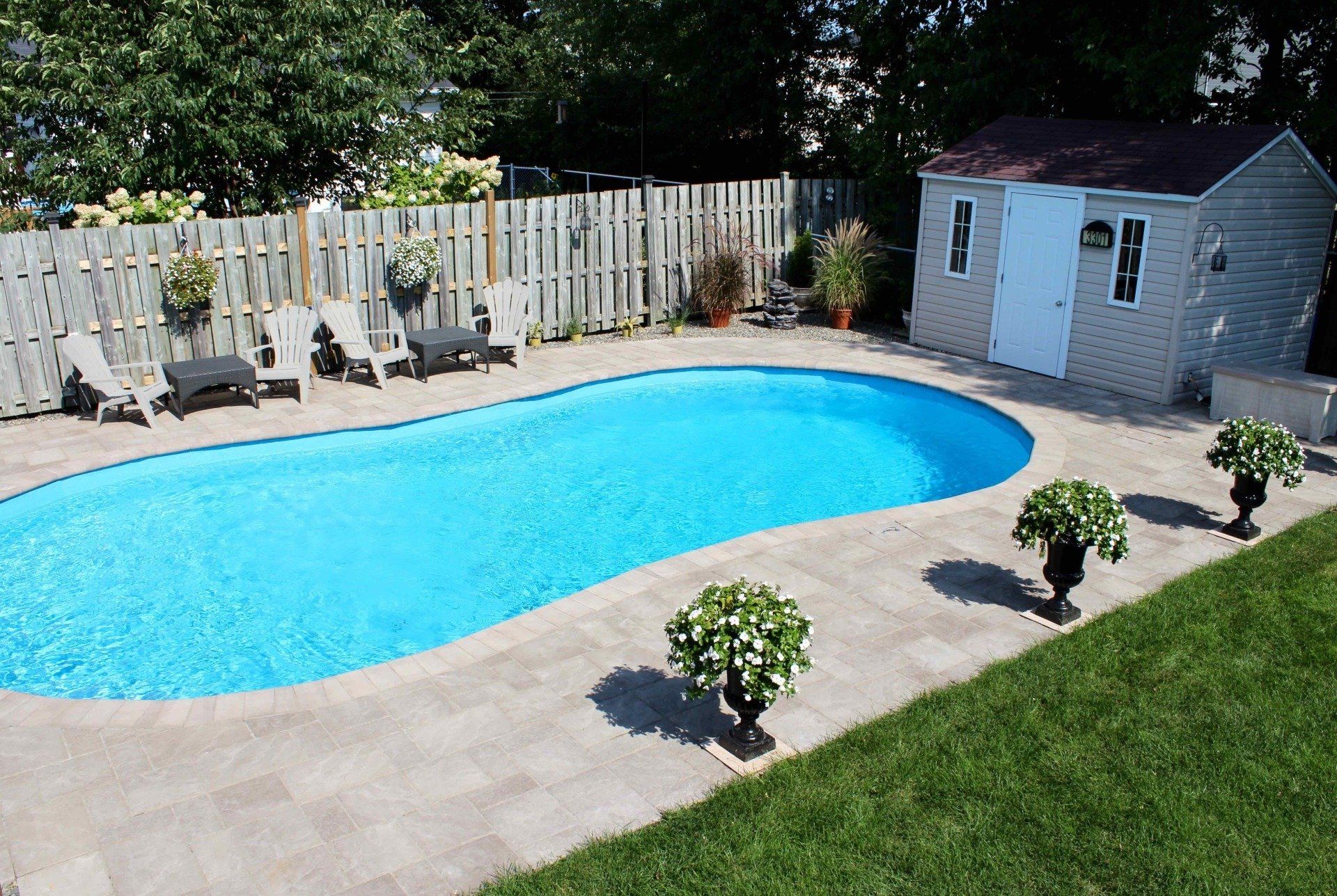 Une grande piscine dans une cour arrière avec des chaises et un cabanon