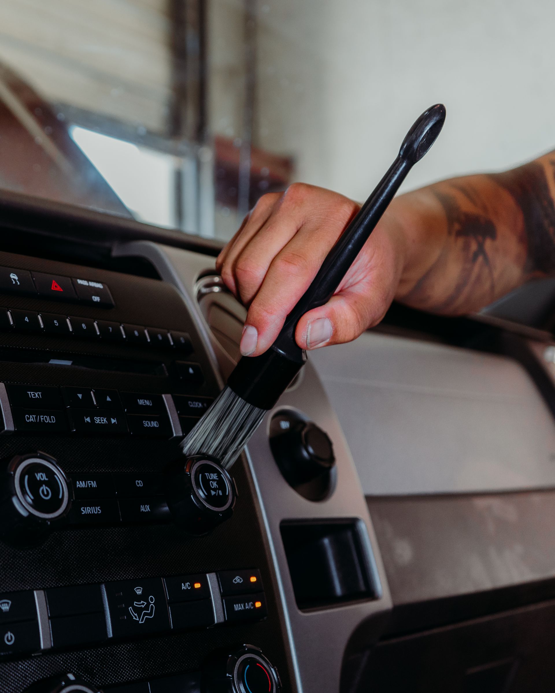 A person is cleaning the dashboard of a car with a brush.