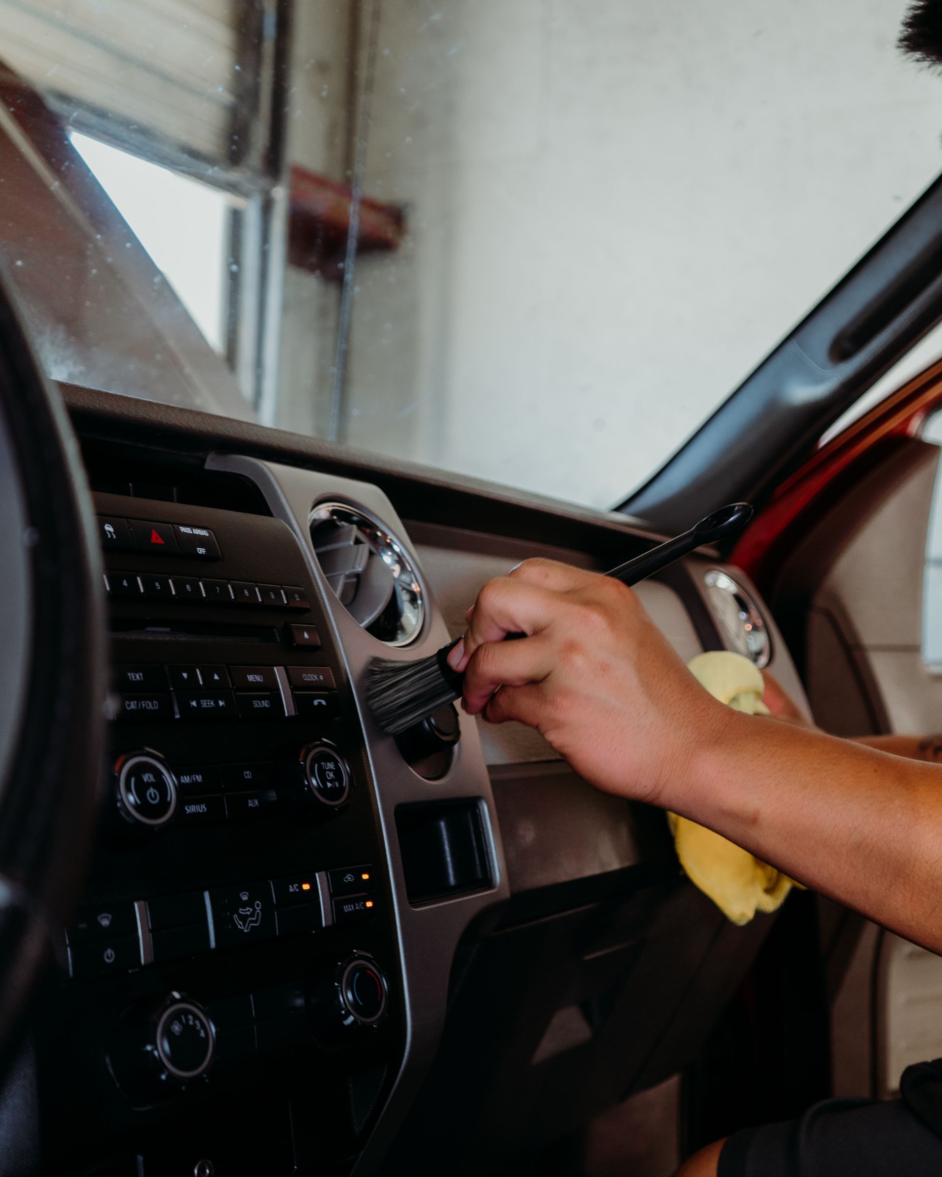 A person is cleaning the dashboard of a car with a cloth.