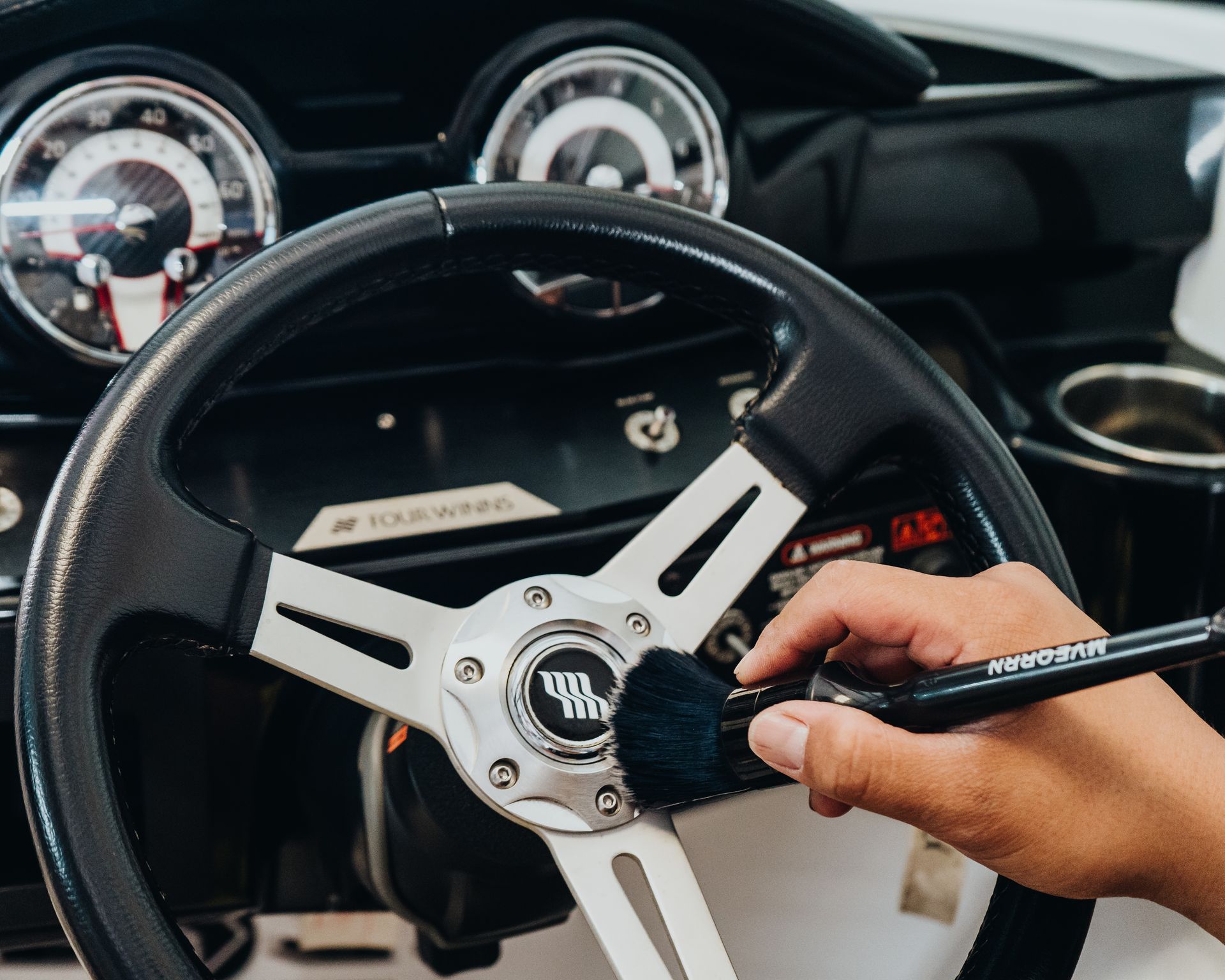 A person is cleaning the steering wheel of a boat with a brush