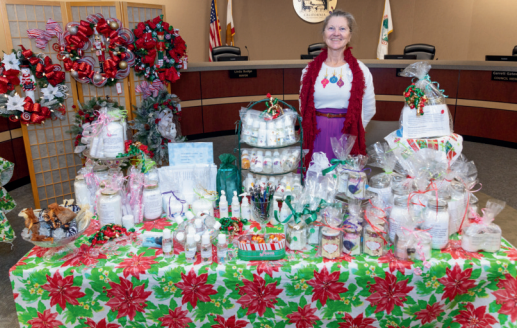 A woman is standing in front of a table filled with lots of christmas decorations.