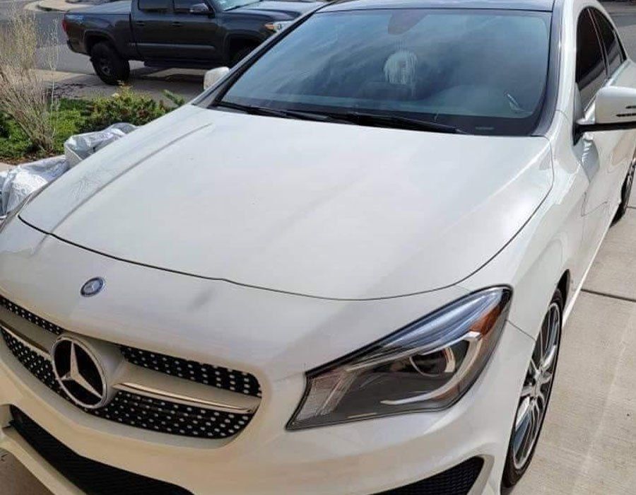 A white mercedes benz is parked in a driveway.