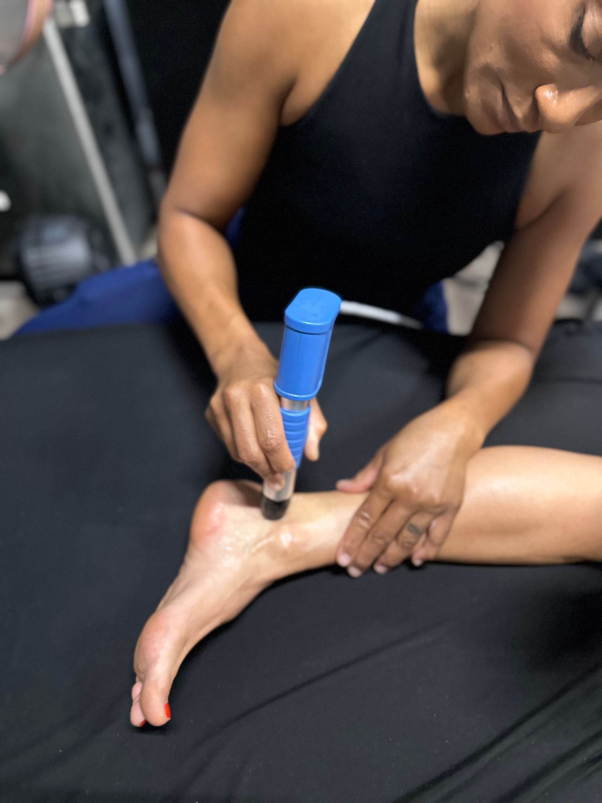 Person administering shockwave therapy to a patient's knee in a medical setting.
