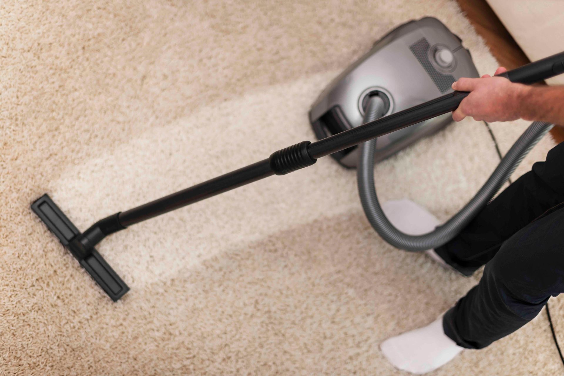 A person is using a vacuum cleaner to clean a carpet.