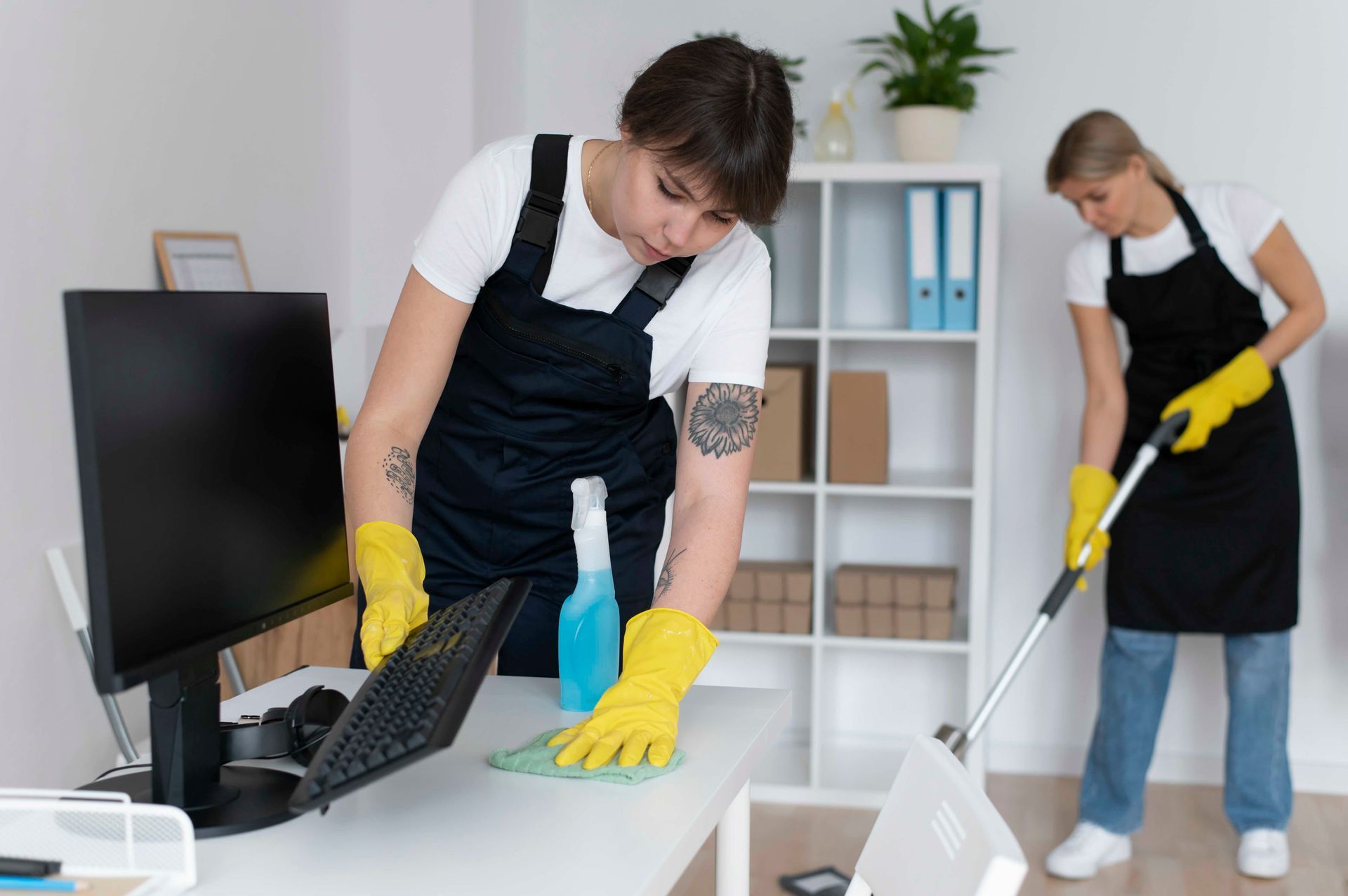 A man and a woman are cleaning a desk in an office.