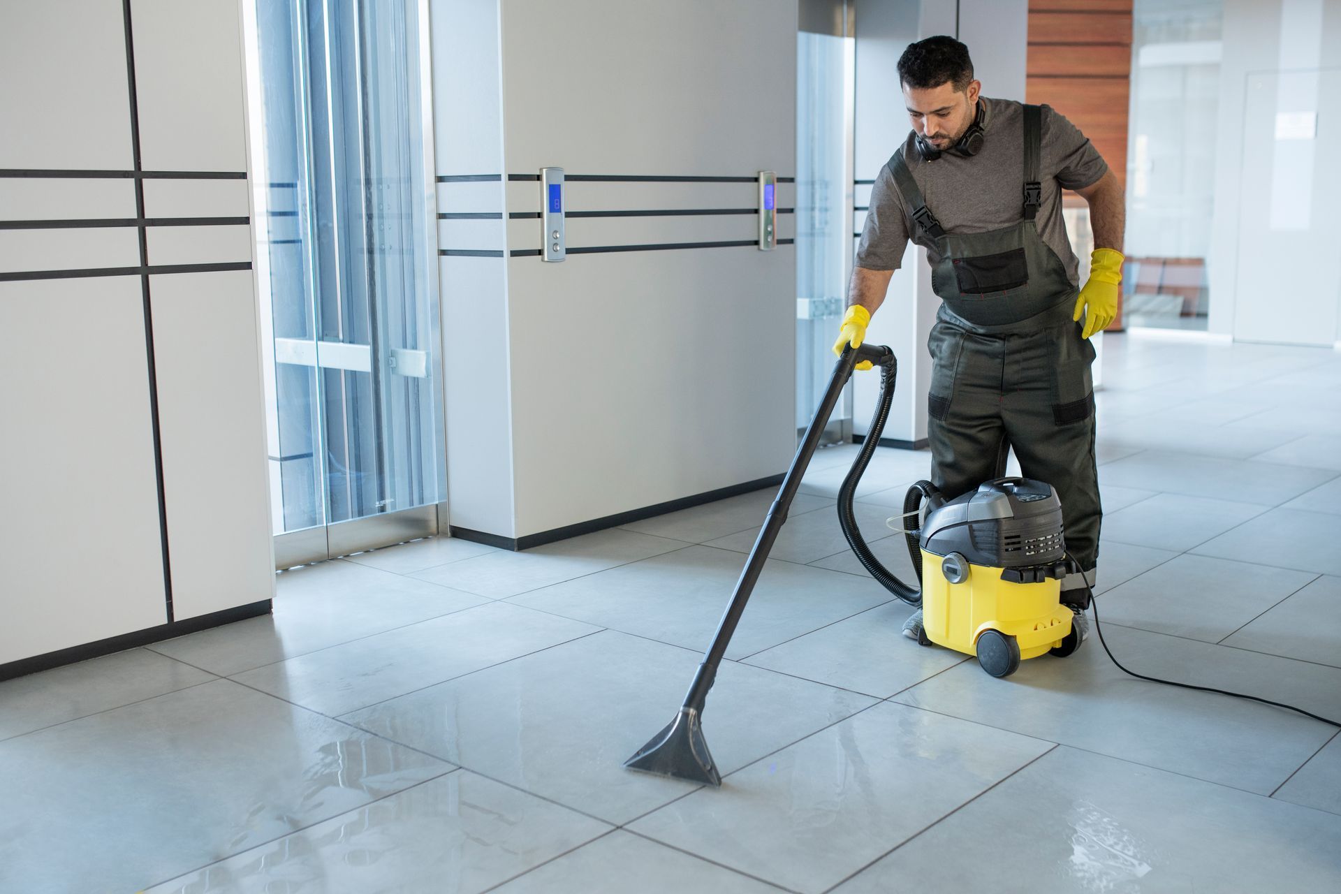 A man is cleaning the floor with a vacuum cleaner.