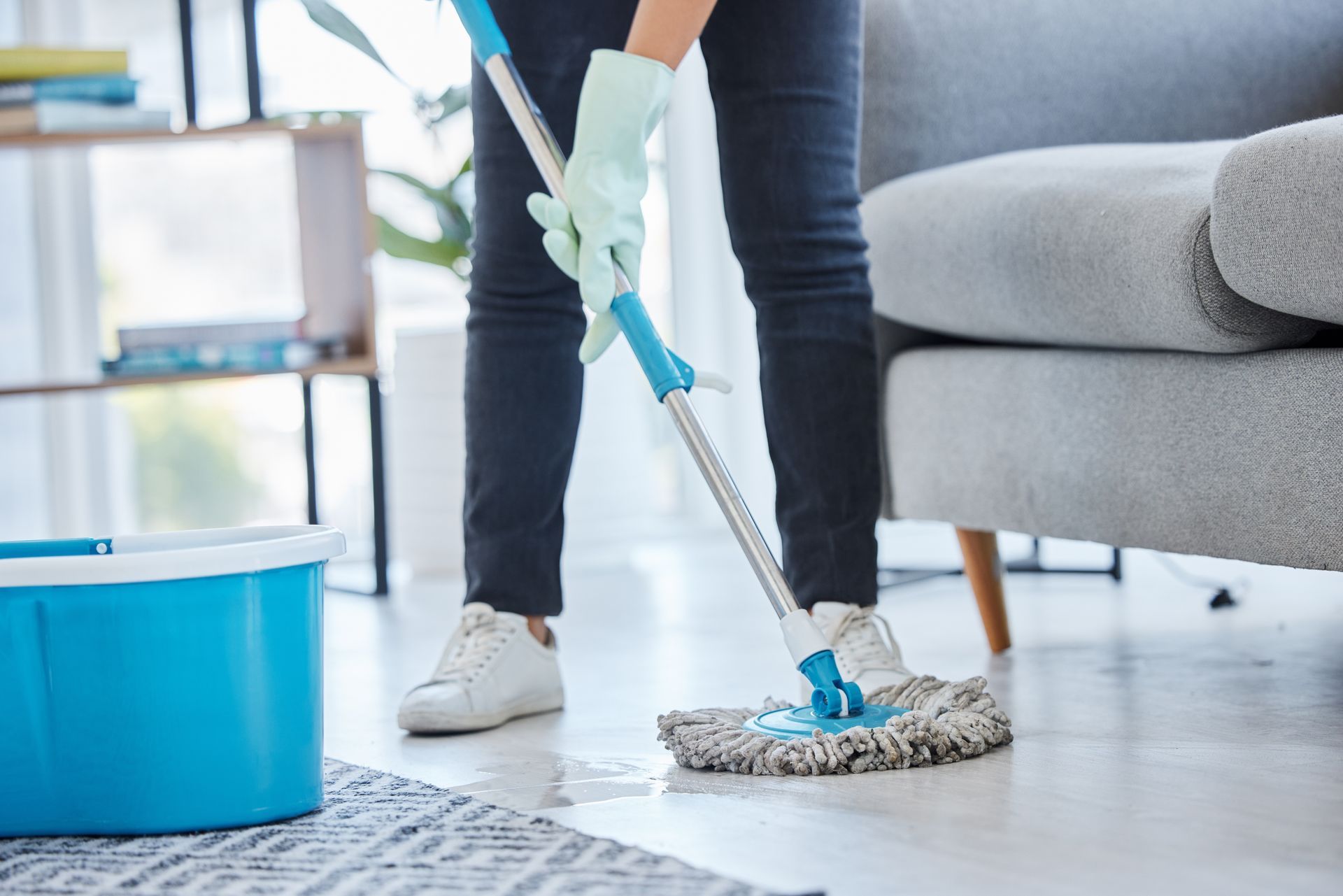 A woman is cleaning the floor with a mop in a living room.