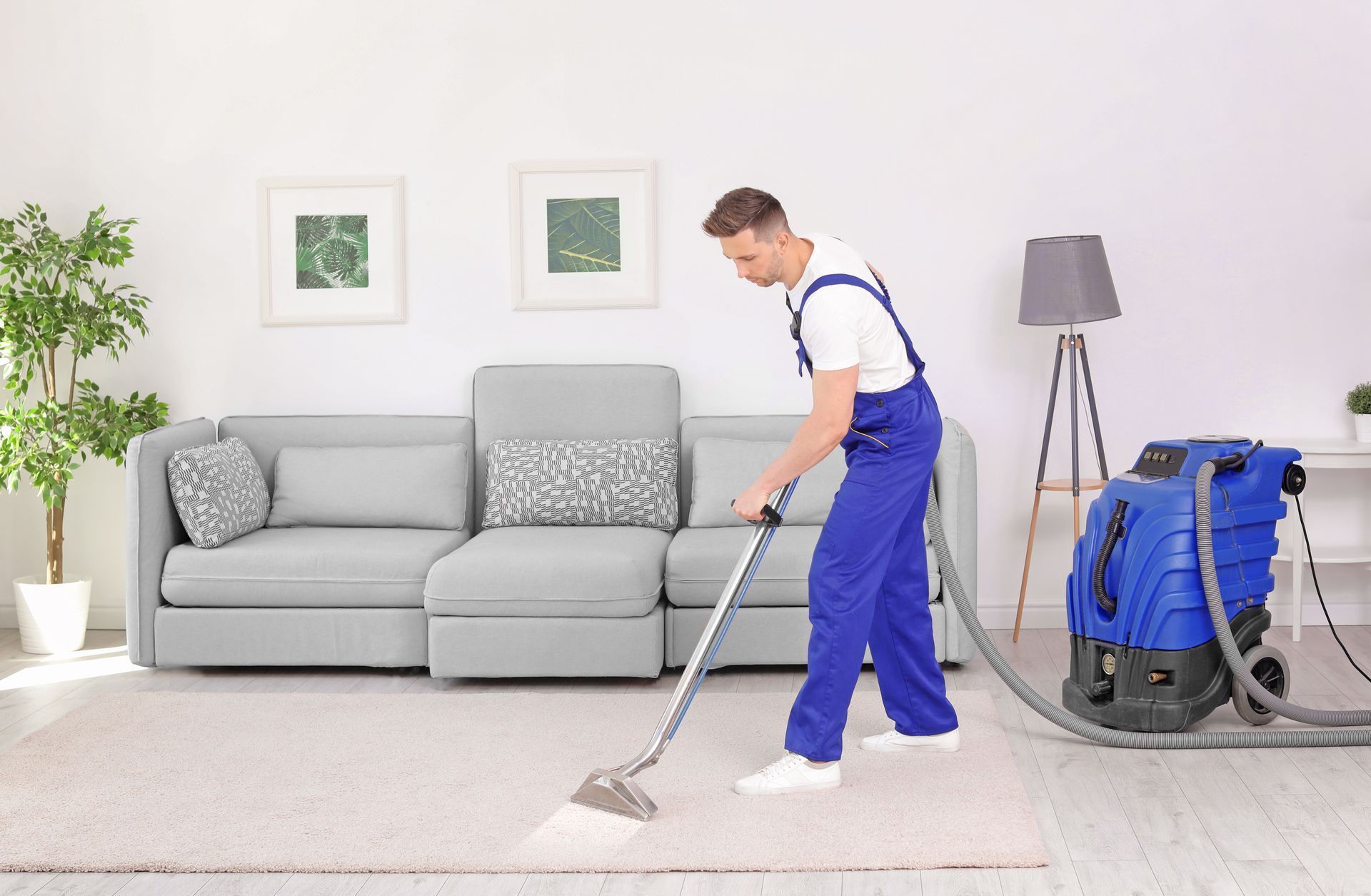 A man is cleaning a carpet with a vacuum cleaner in a living room.