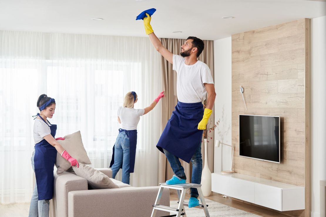 A man and a woman are cleaning a living room.