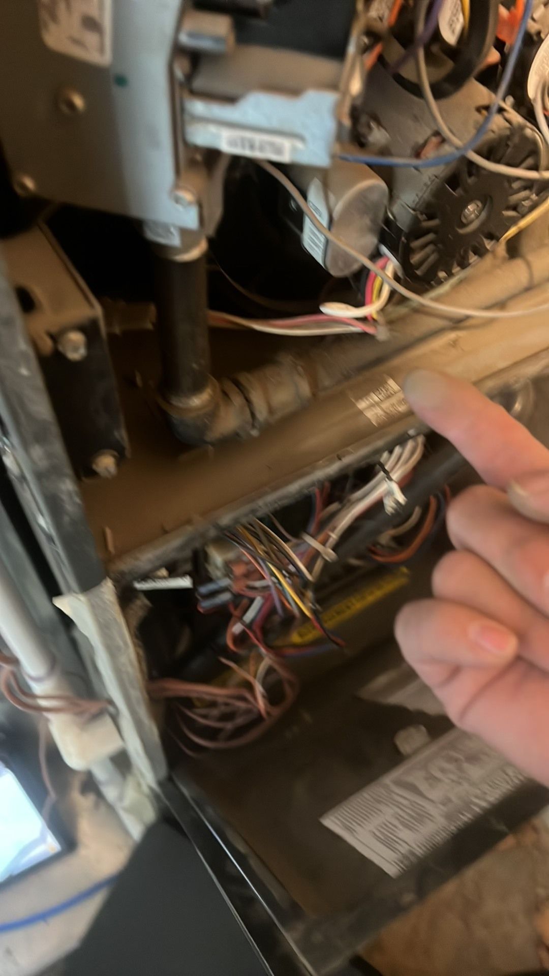 Comfy Castle Heating and Air - A person is pointing at a bunch of wires on a machine.