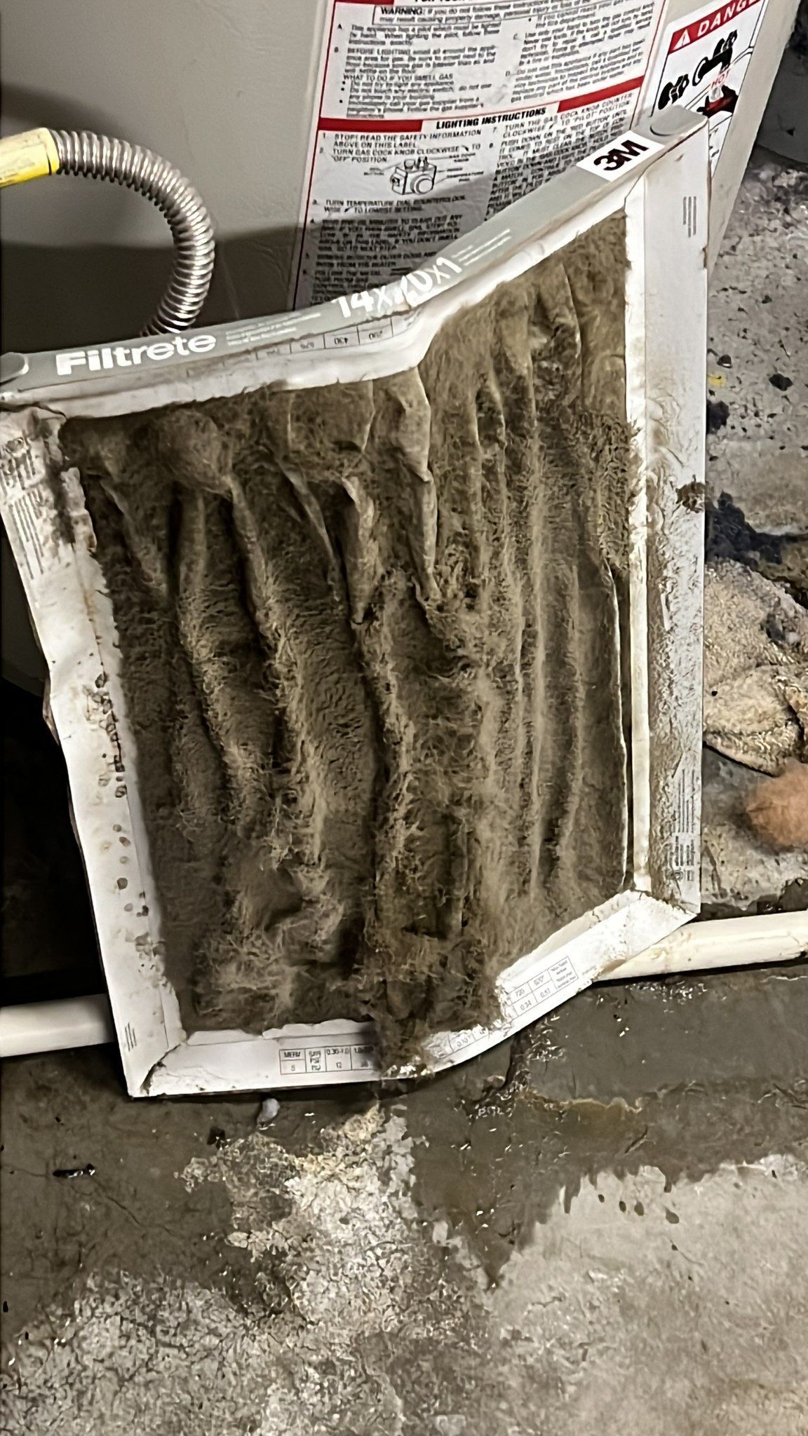 Comfy Castle Heating and Air - A dirty air filter is sitting on the floor next to a hose.