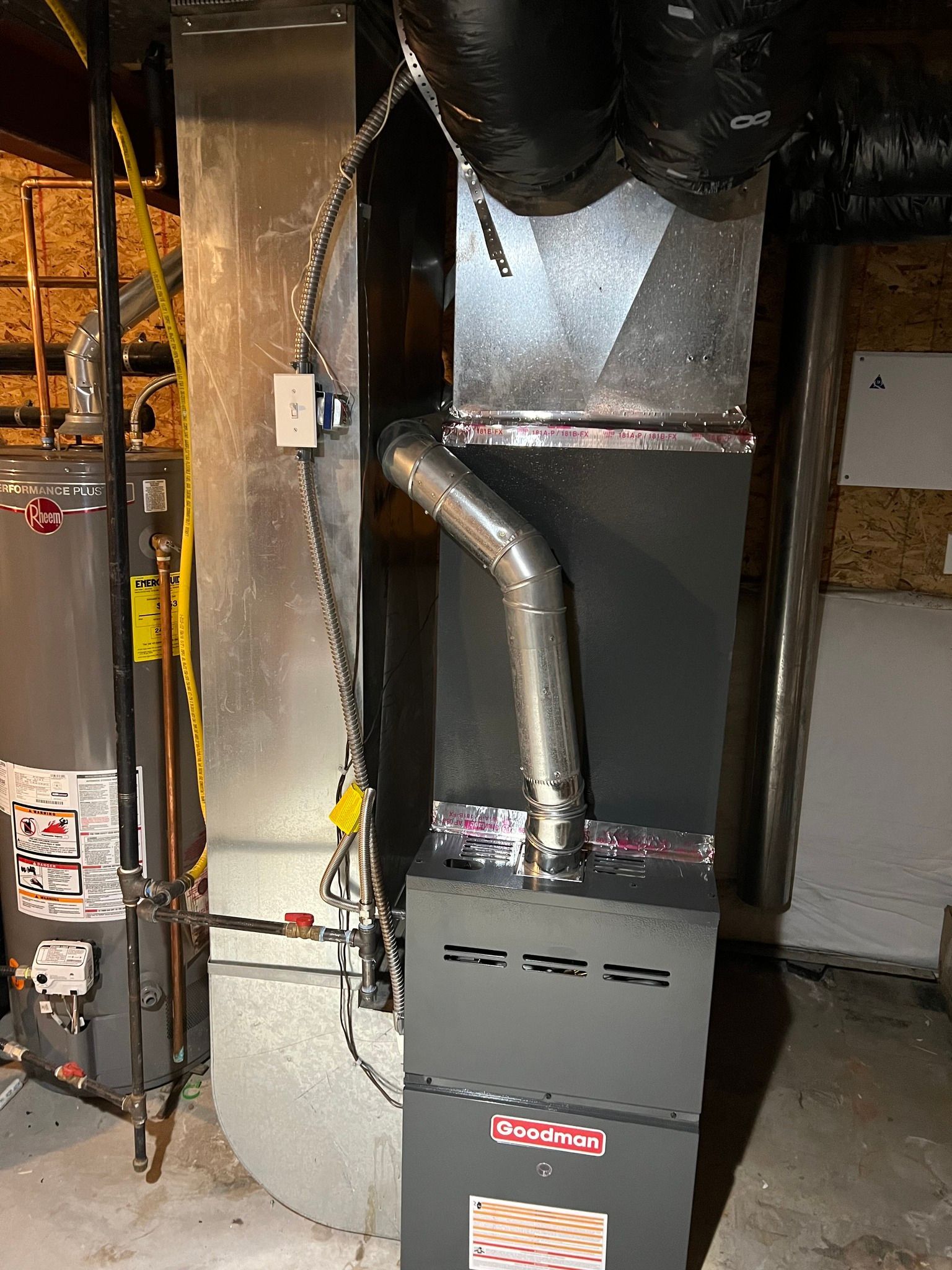 Comfy Castle Heating and Air - A furnace is sitting in a basement next to a water heater.