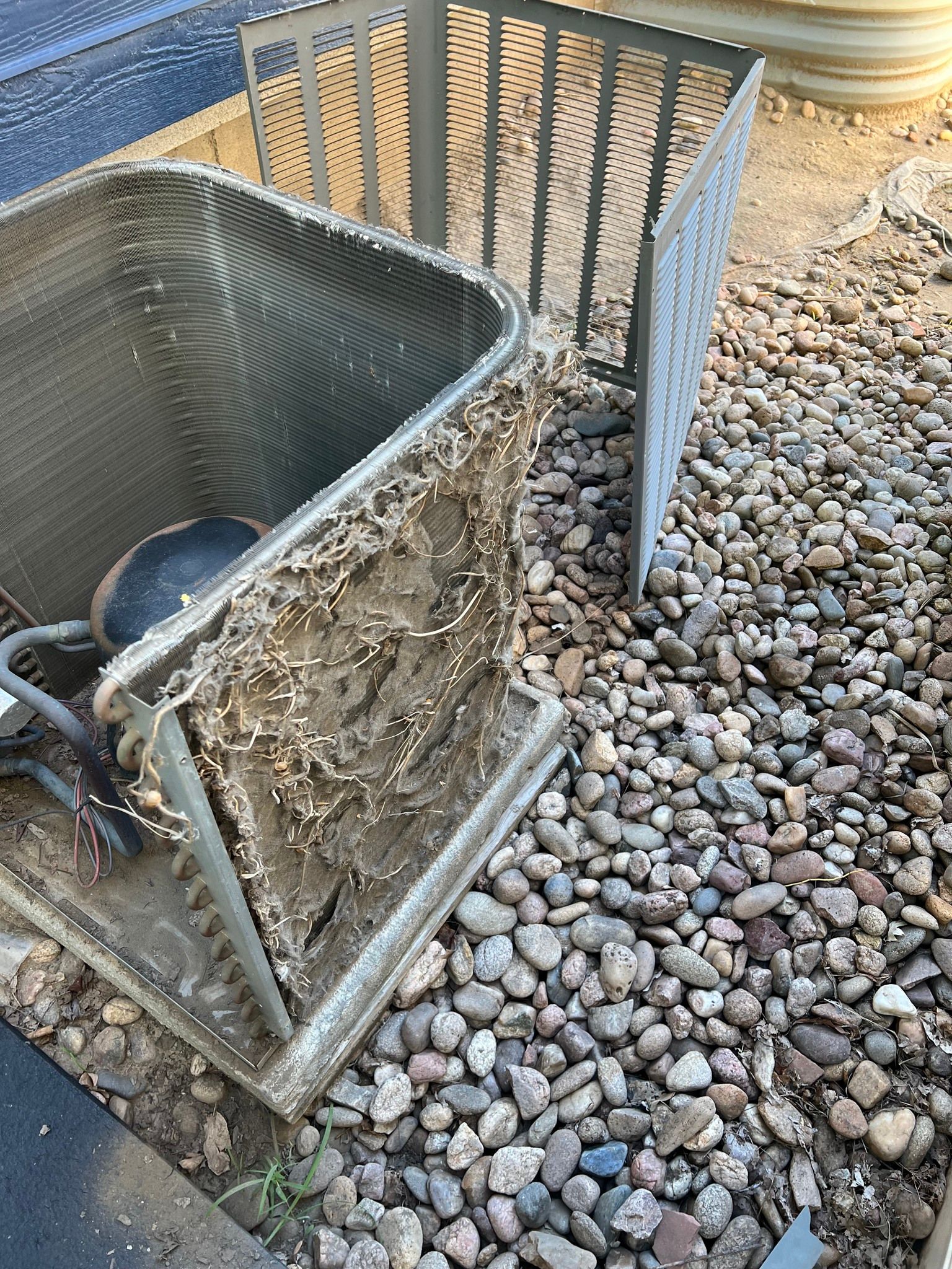 Comfy Castle Heating and Air - A dirty air conditioner is sitting on top of a pile of rocks.