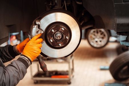 A mechanic is fixing a brake disc on a car in a garage.