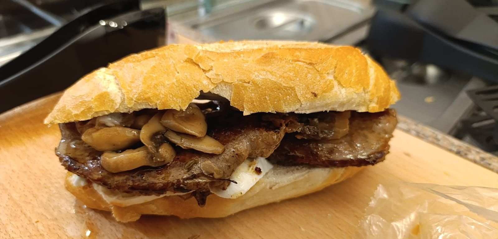 Waffle ricoperto di salsa al cioccolato, glassa bianca e granella, servito su un piatto di carta, tenuto in mano da una persona che indossa una maglietta verde.