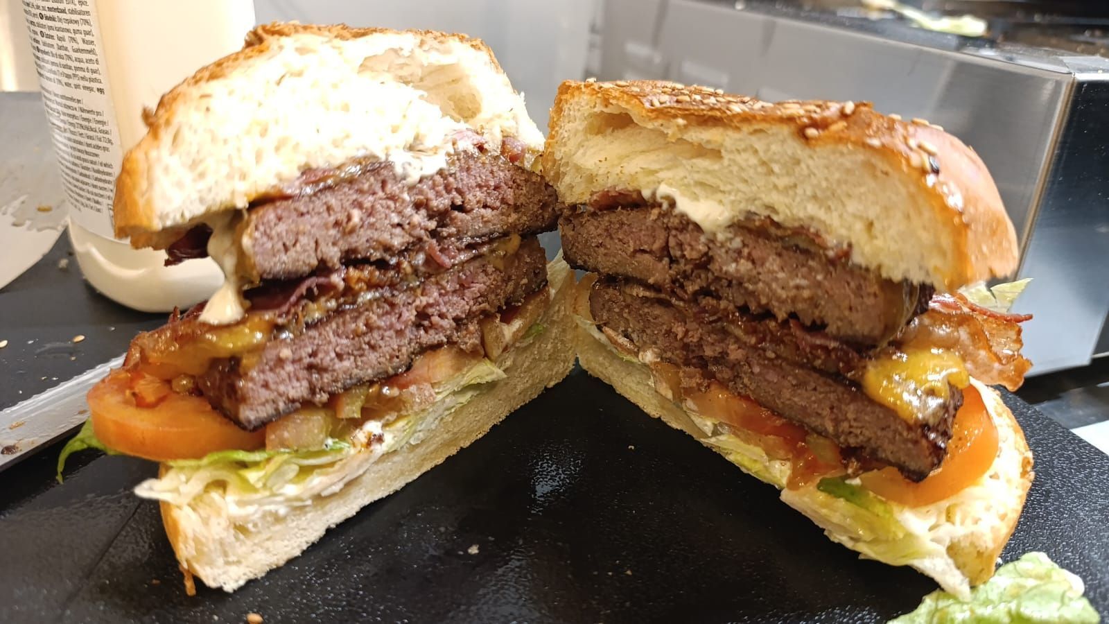 Hamburger doppio tagliato a metà, che rivela la carne di manzo, i condimenti e il panino.