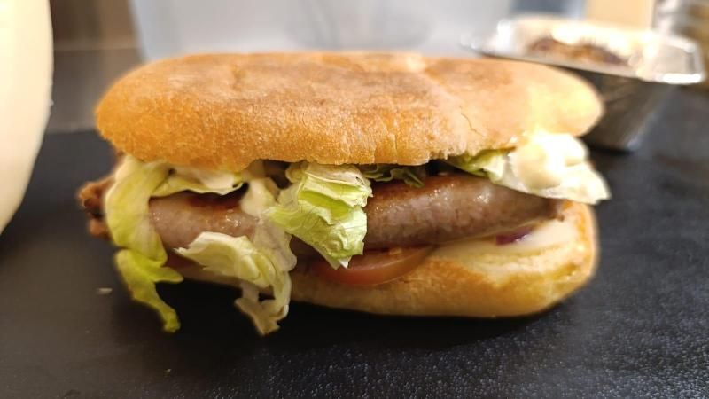 Hamburger in un panino con lattuga, pomodoro e salsa.