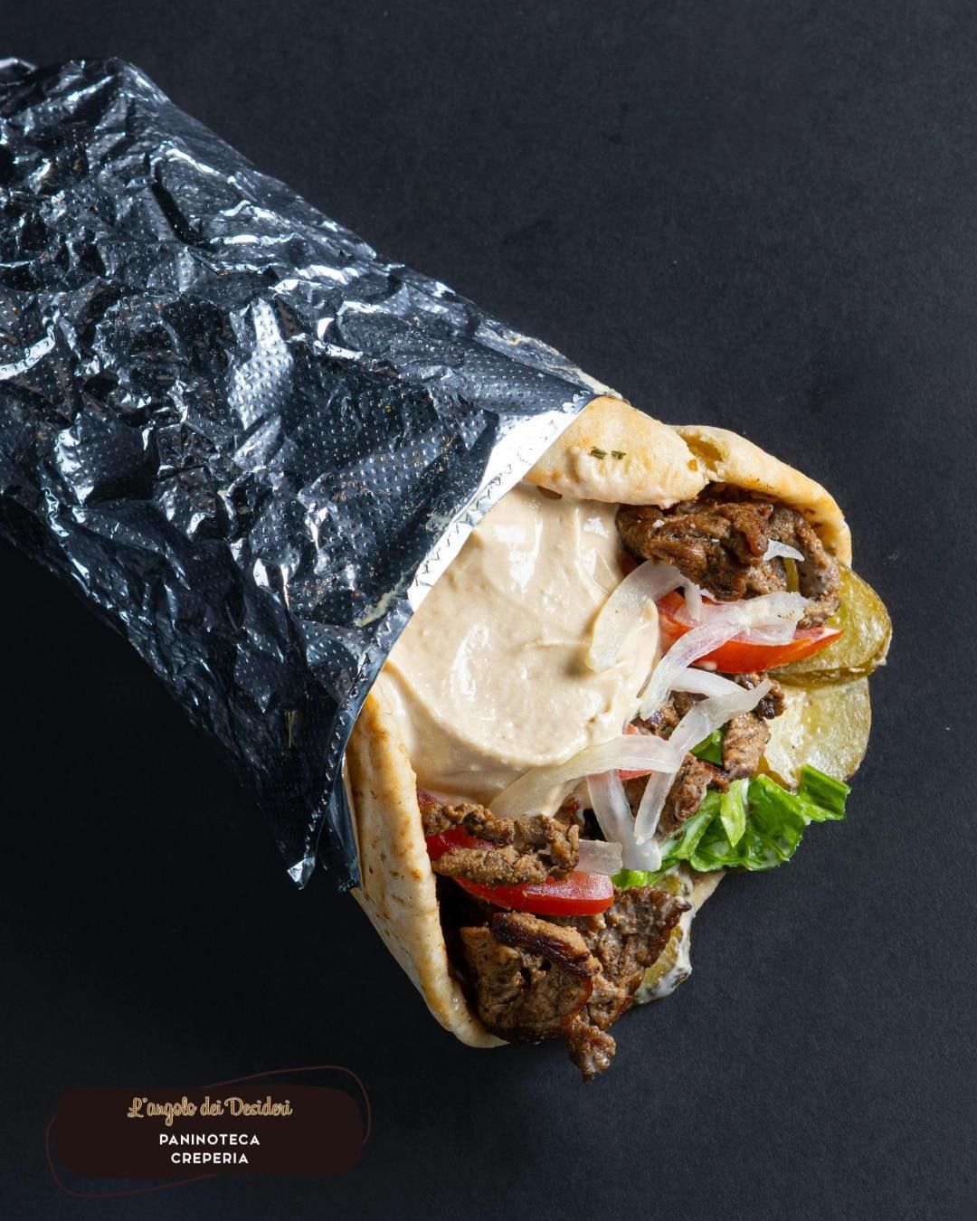 Persona che tiene in mano un parfait, con indosso una camicia verde acqua. Il parfait è composto da strati di salsa rossa, crema bianca e frutti di bosco.