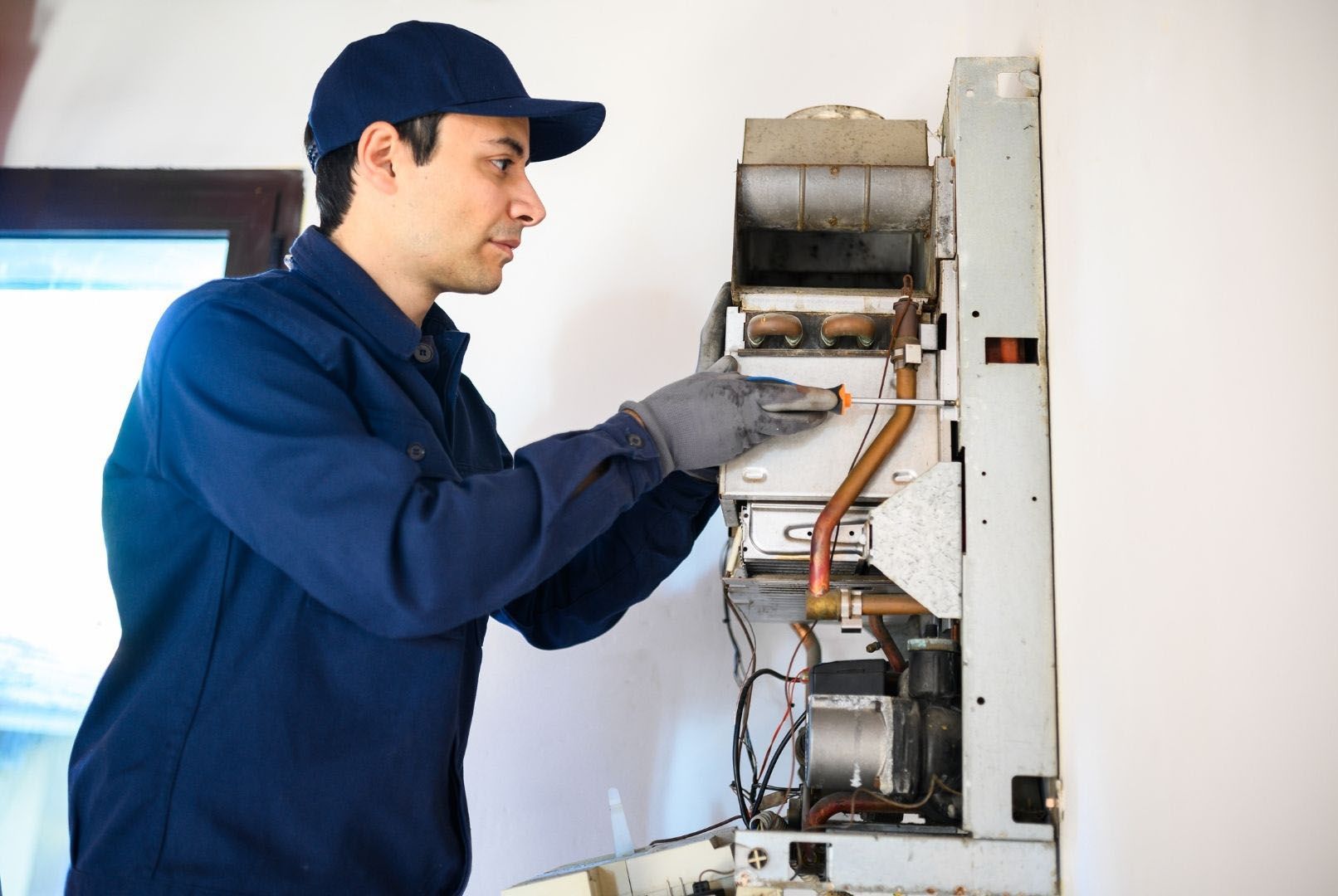 A man is fixing a boiler with a wrench.