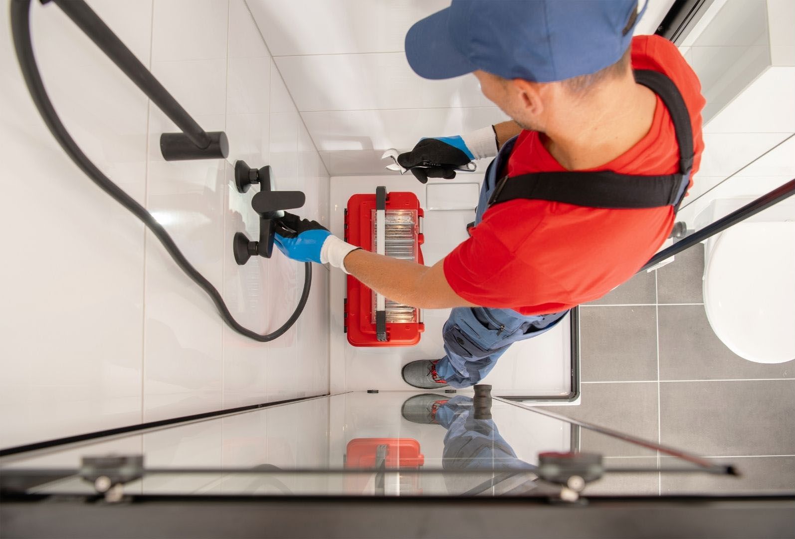A plumber is working on a drain in a bathroom.