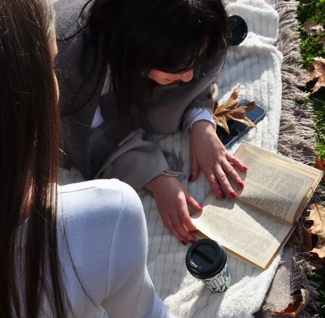 Friends chatting outdoors in a garden, seated on cushions with trees and greenery around them