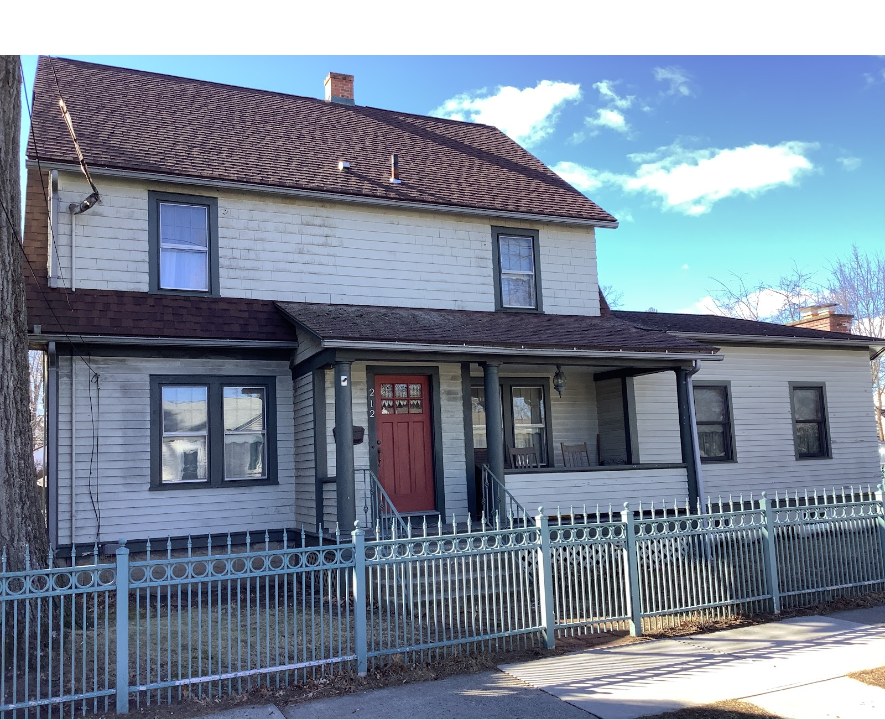 a tan house with a red door and a blue fence prior to new exterior paint