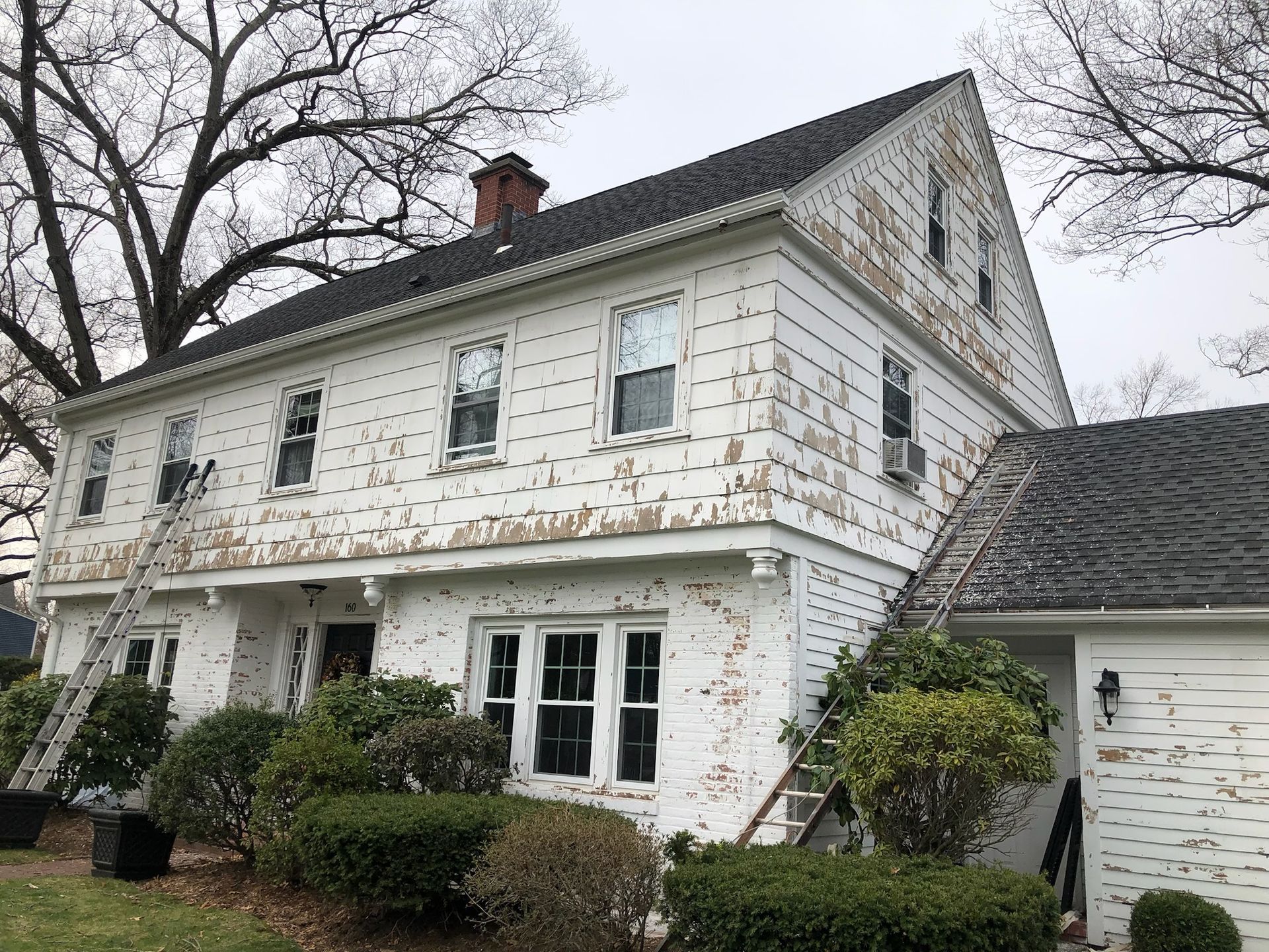 a large white house with a black roof is being painted .