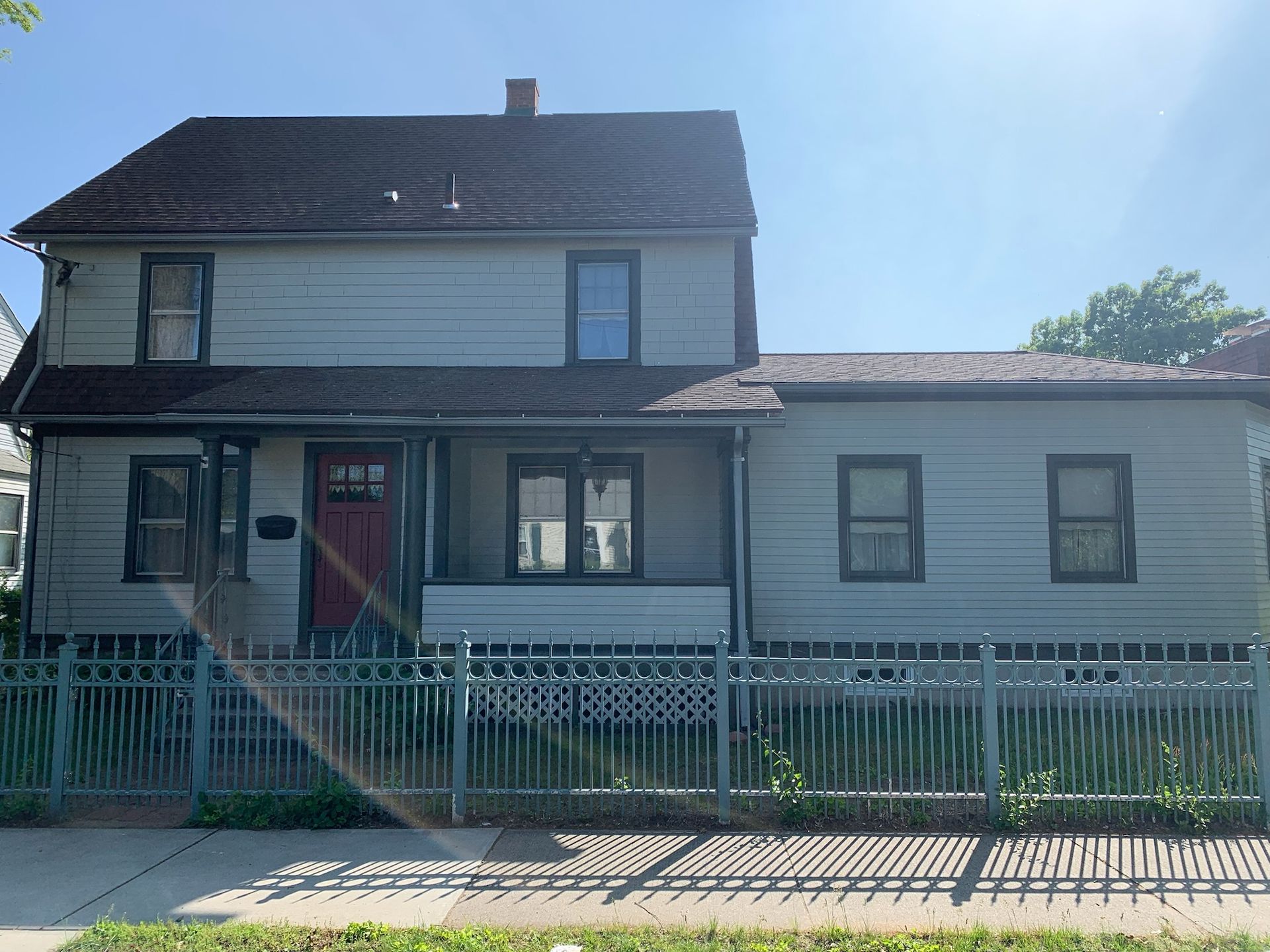 a house with a fence around it and a red door after new exterior paint