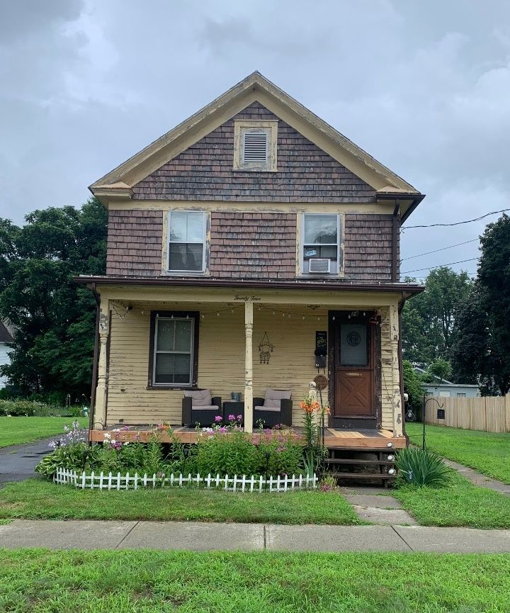 a house with a porch and a fence in front of it