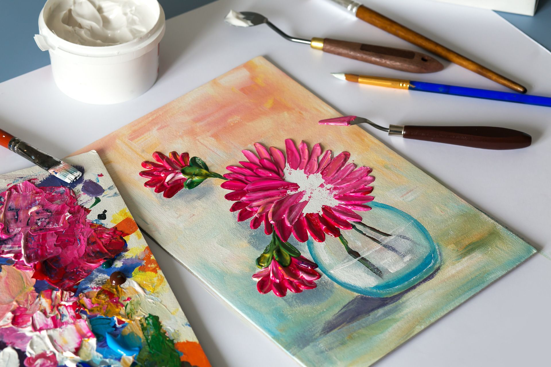 A painting of flowers in a vase with brushes and paint