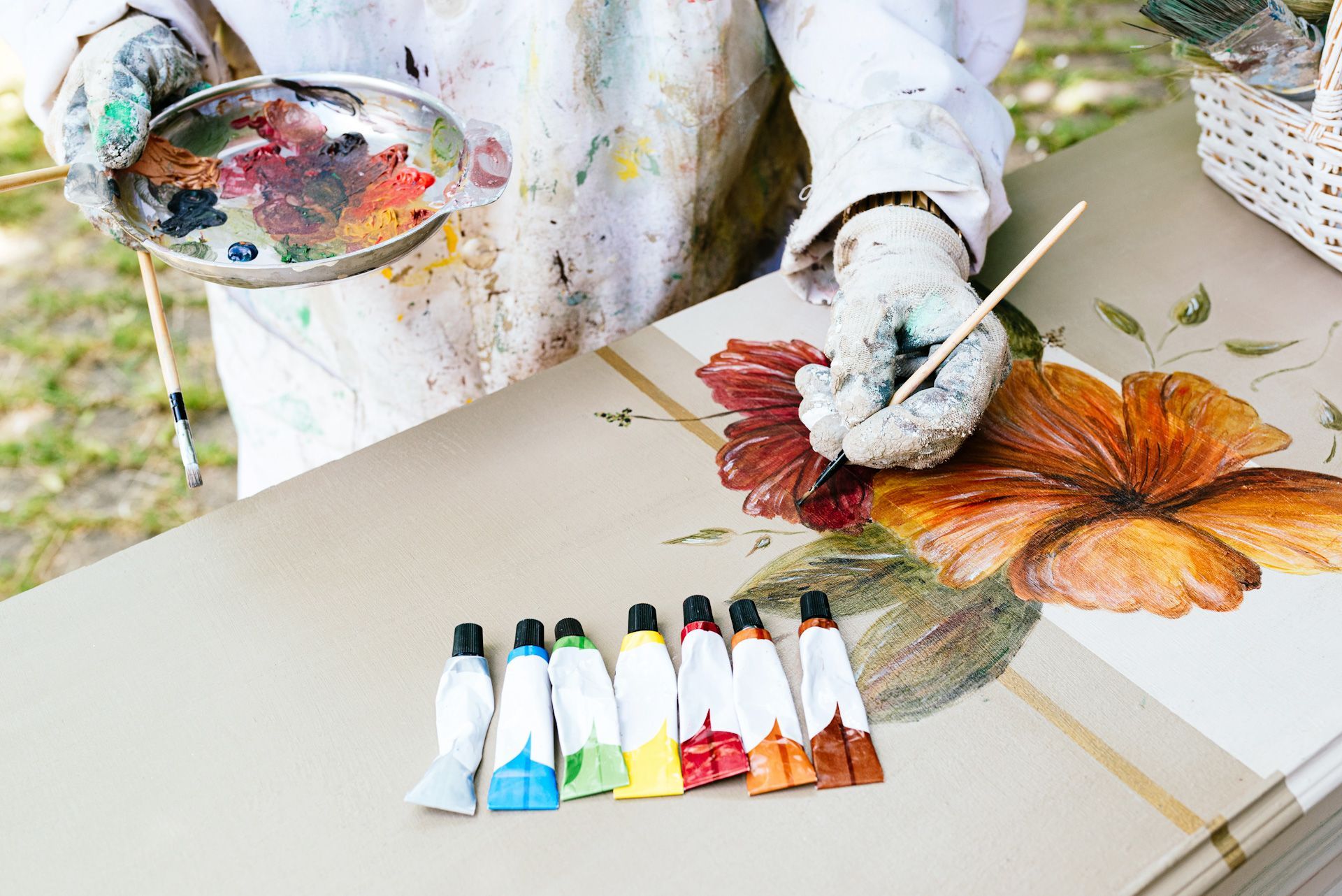A person is painting a flower on a table with a palette and brush