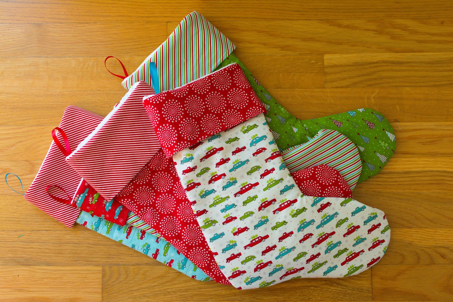 Three Christmas stockings are stacked on top of each other on a wooden table