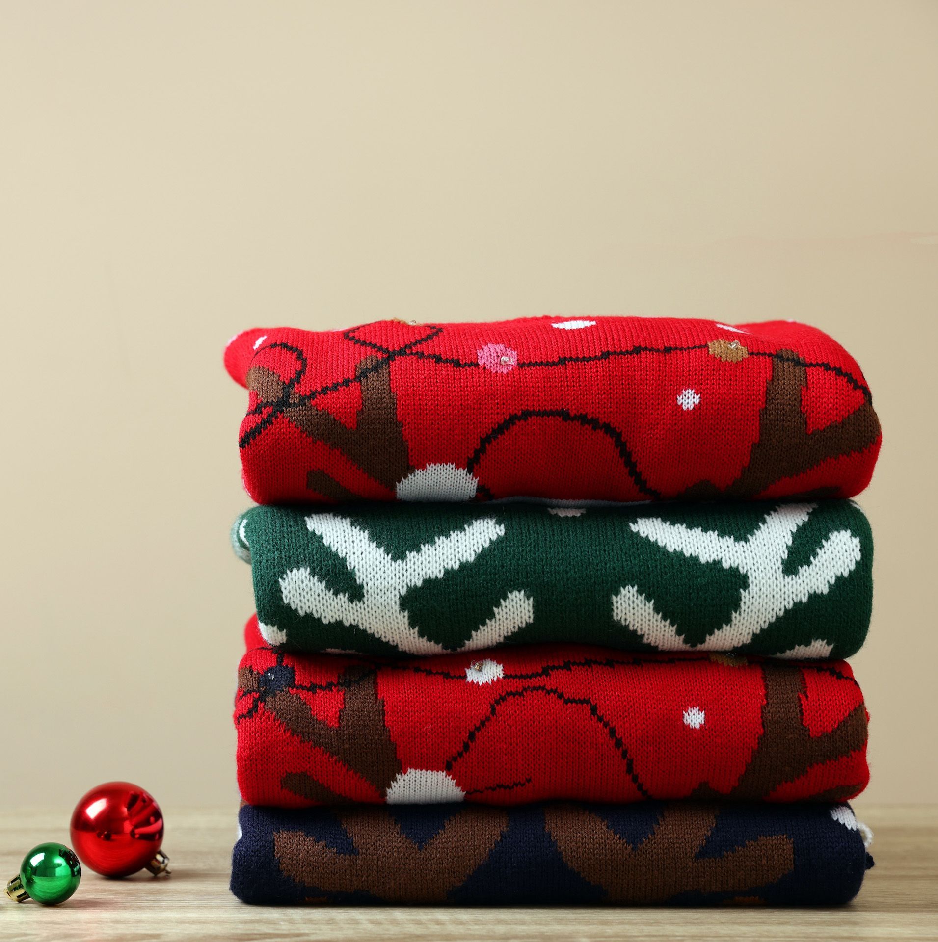 Three Christmas sweaters are stacked on top of each other on a table