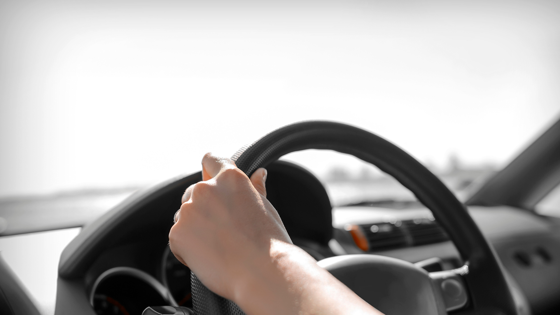 A person 's hand is on the steering wheel of a car