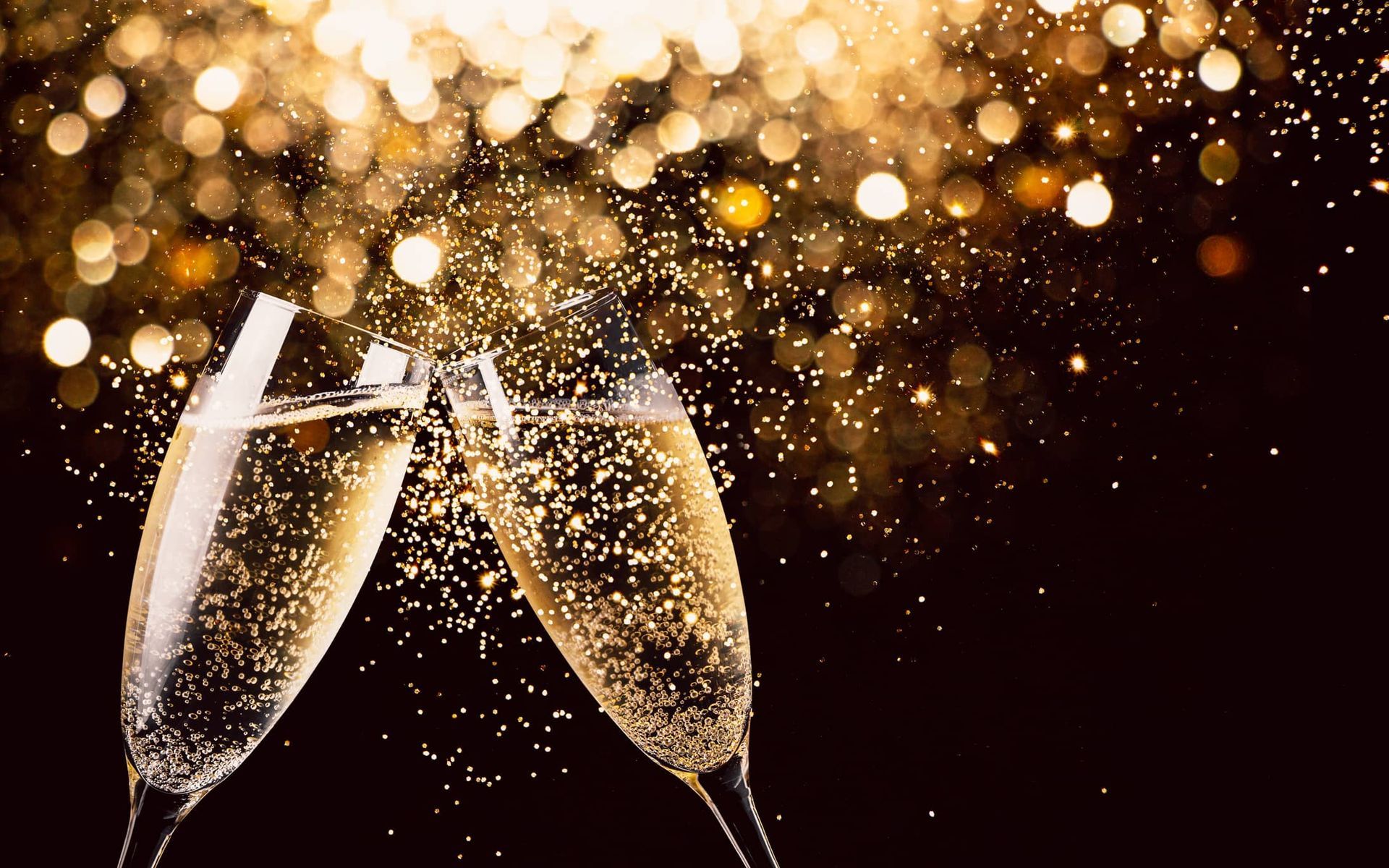 two glasses of champagne are toasting with sparklers in the background .