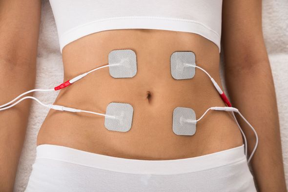 Una zona abdominal con cuatro electrodos blancos conectados mediante cables a un dispositivo de terapia EMS.