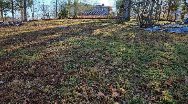 A large grassy field with a house in the background.