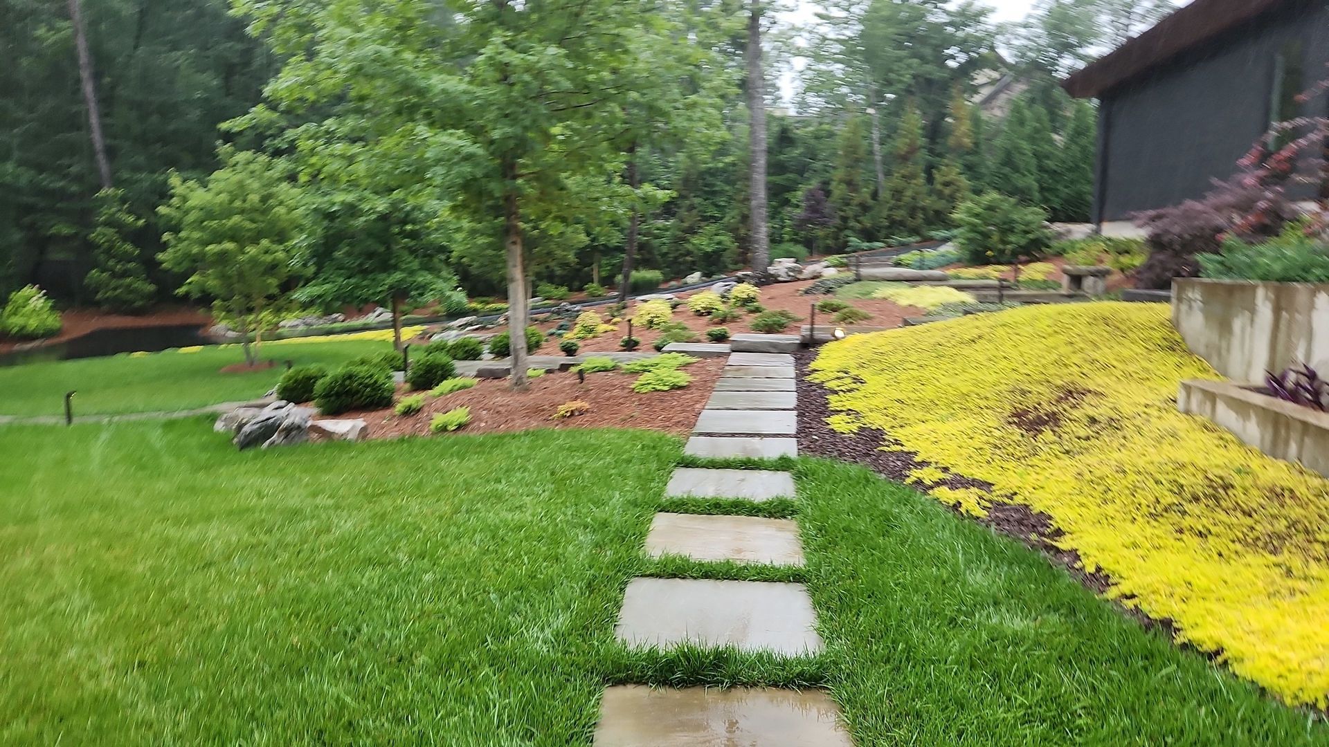 A stone walkway leading to a house in a garden