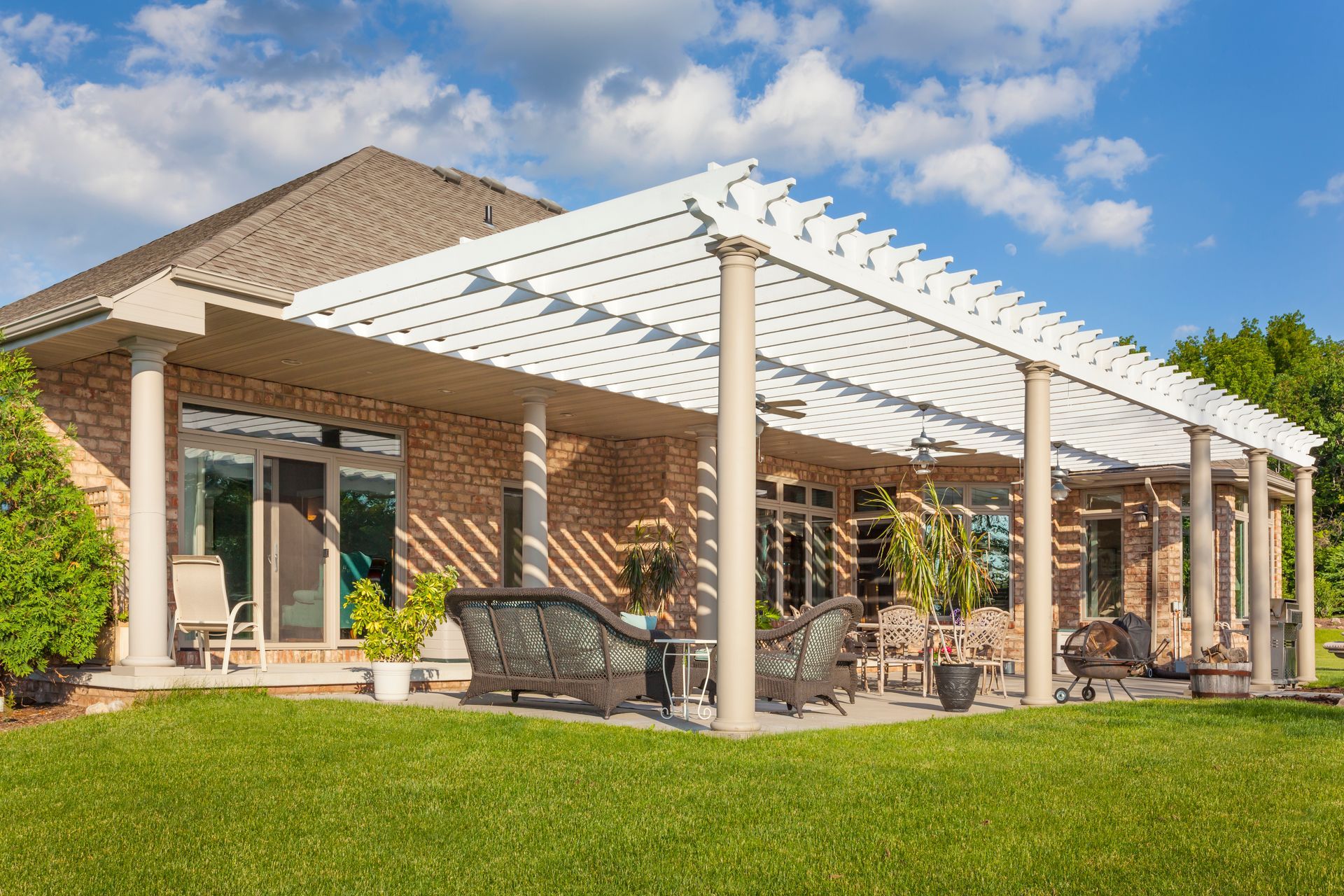 A brick house with a white pergola and patio furniture