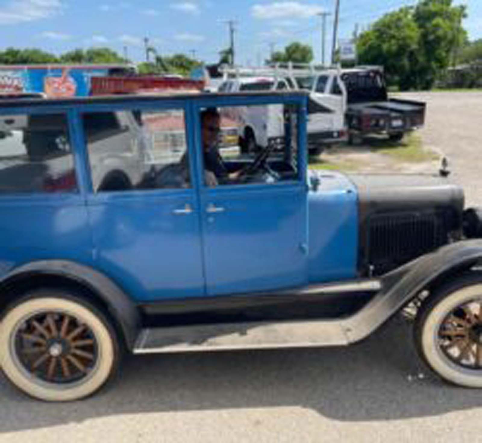 An old blue car is parked in a parking lot.