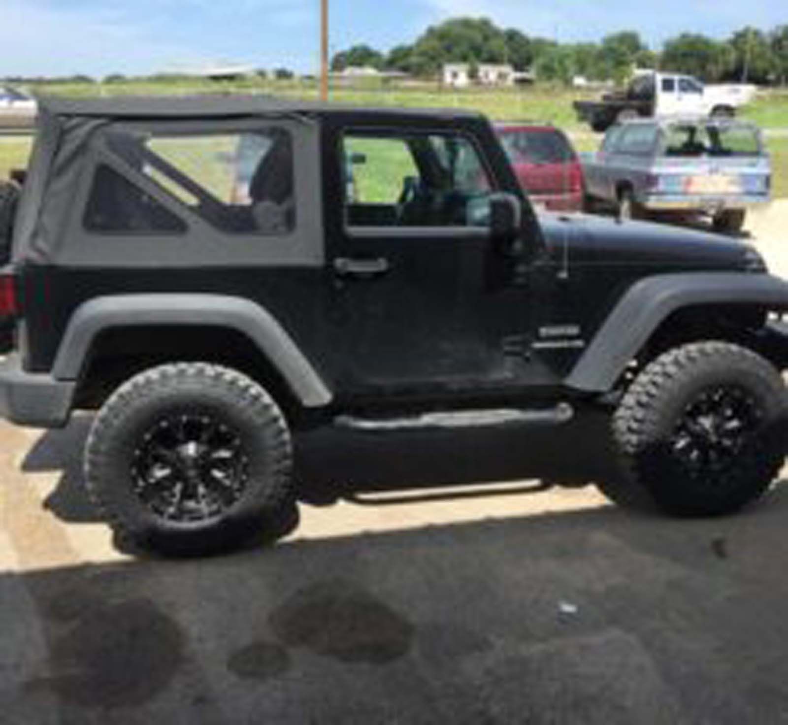 A black jeep is parked in a parking lot.