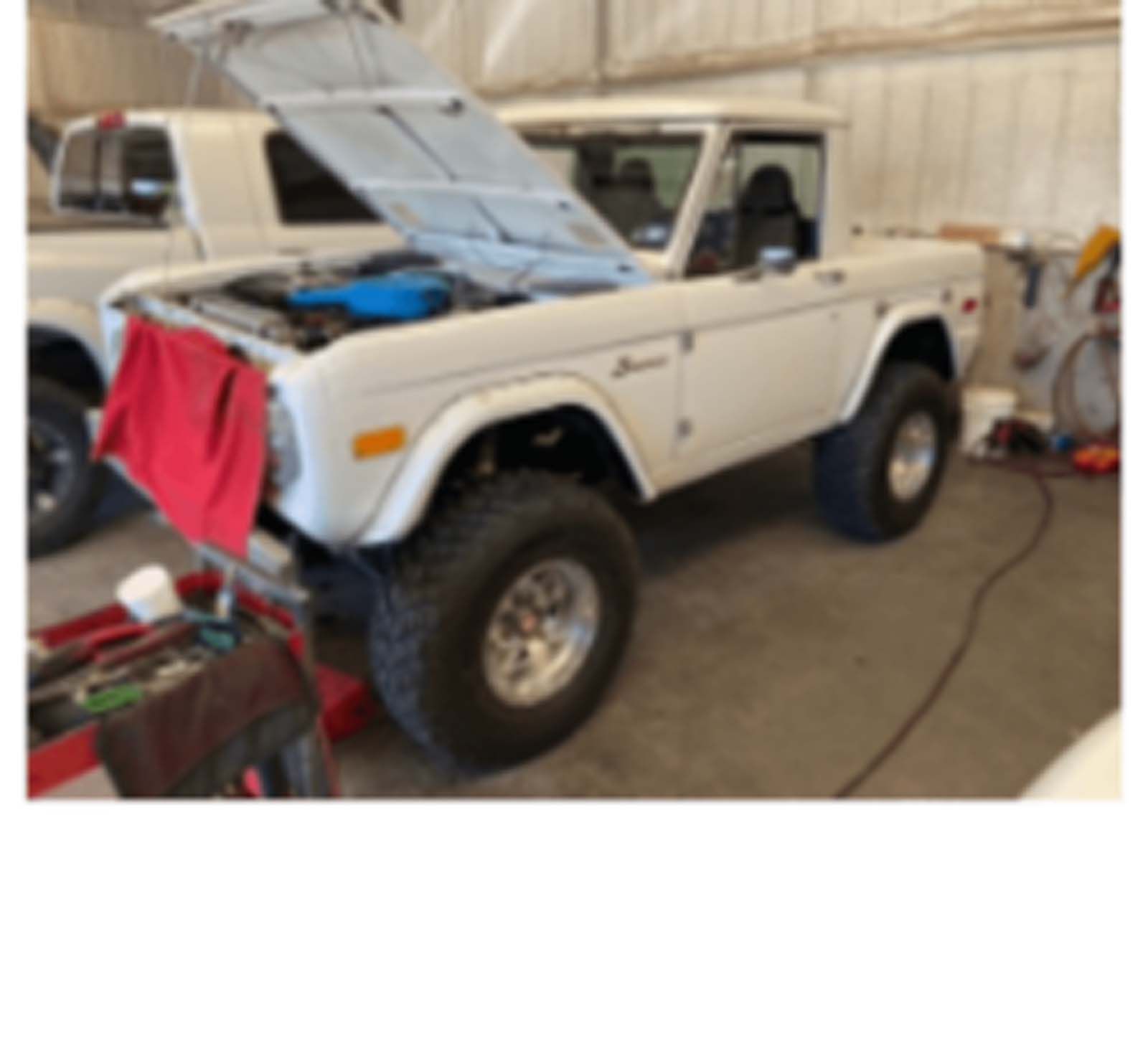 A white truck with the hood up in a garage