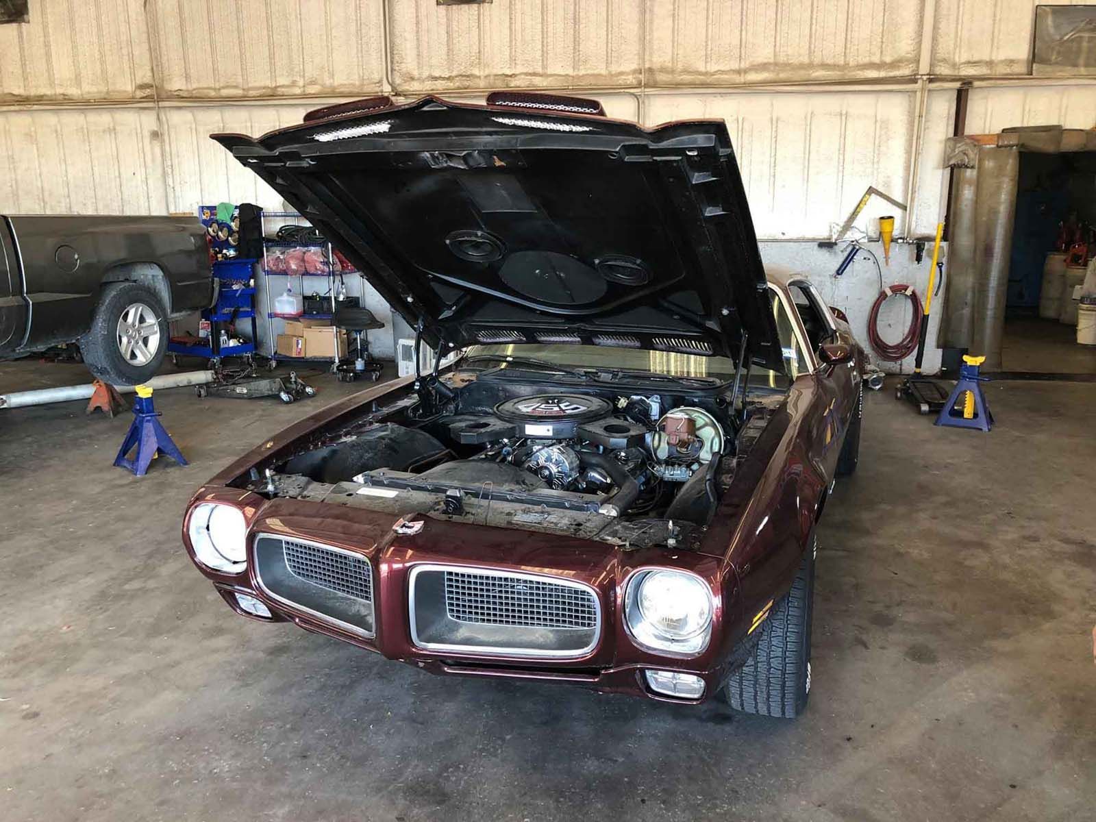 A red pontiac gto with the hood up in a garage.