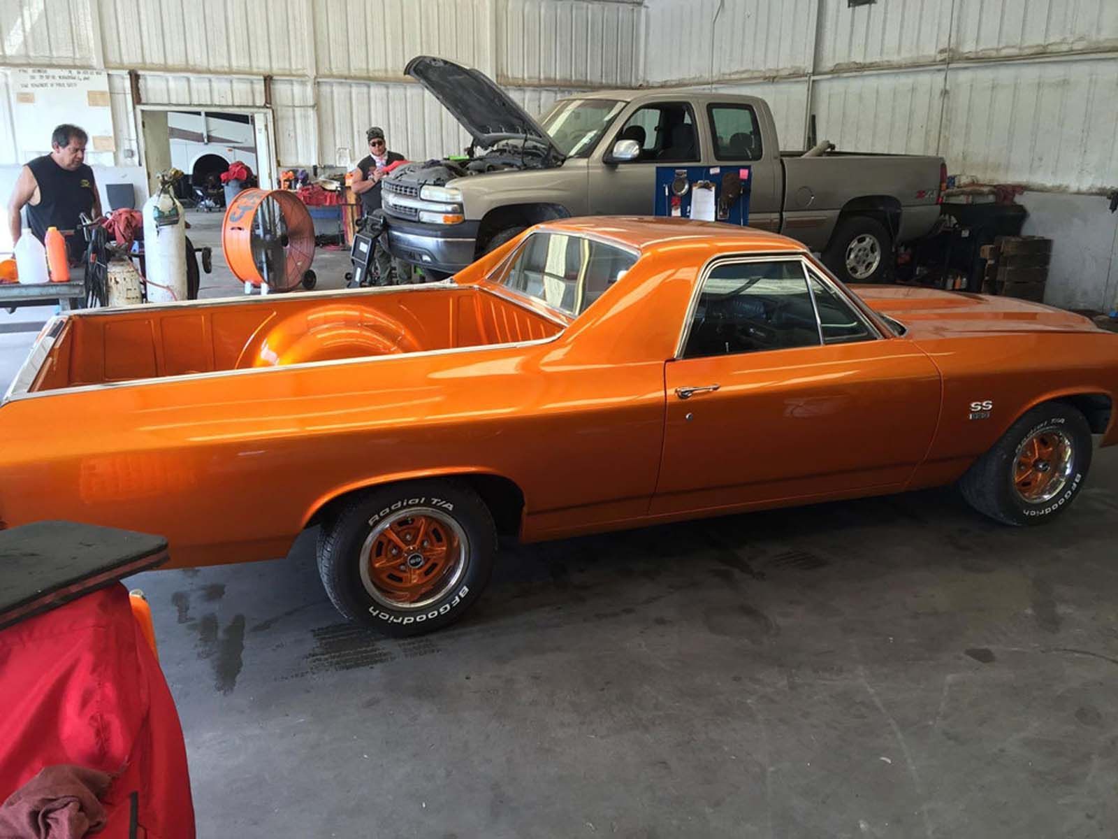 An orange pickup truck is parked in a garage