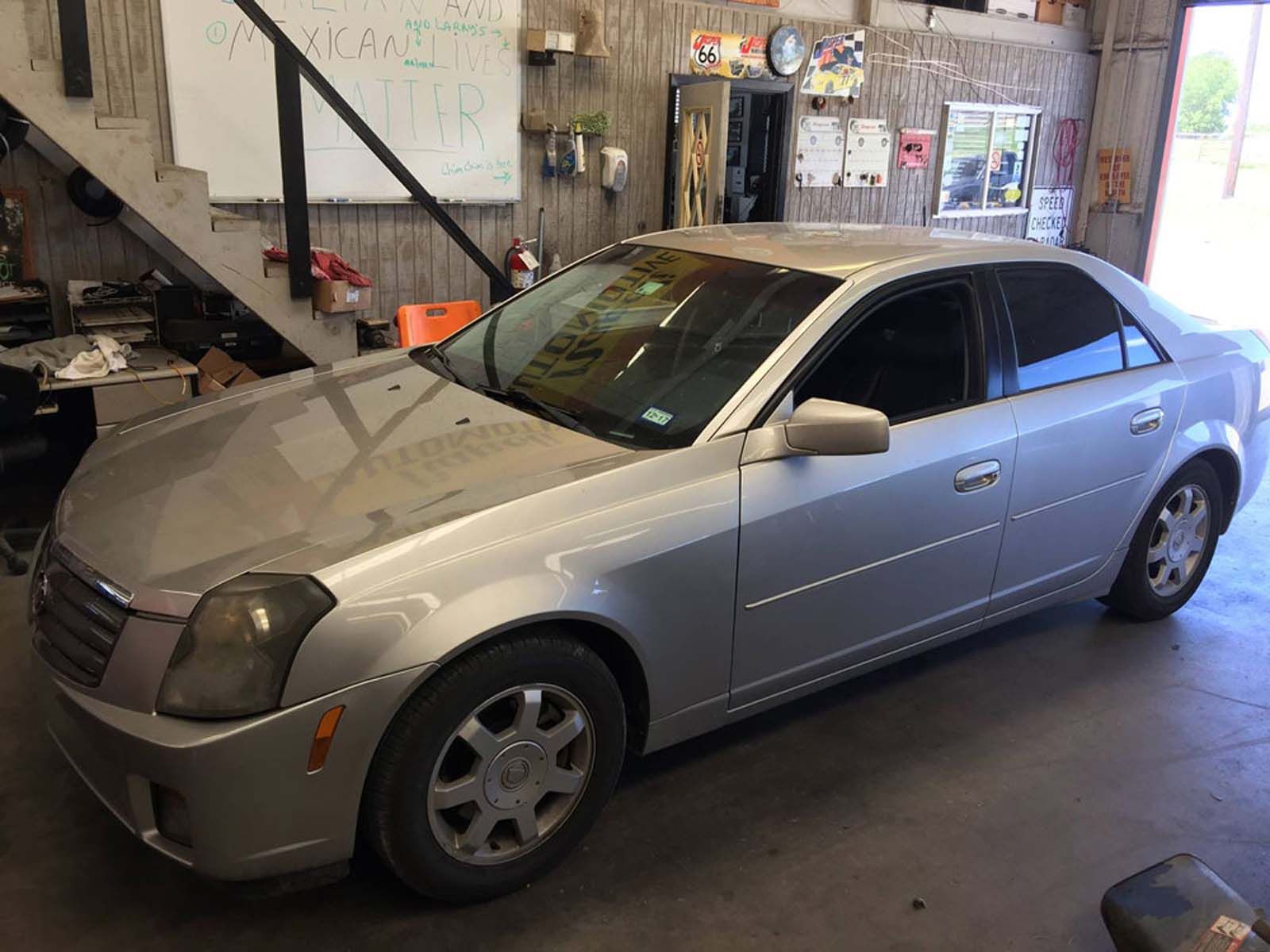 A silver car is parked in a garage next to a staircase.