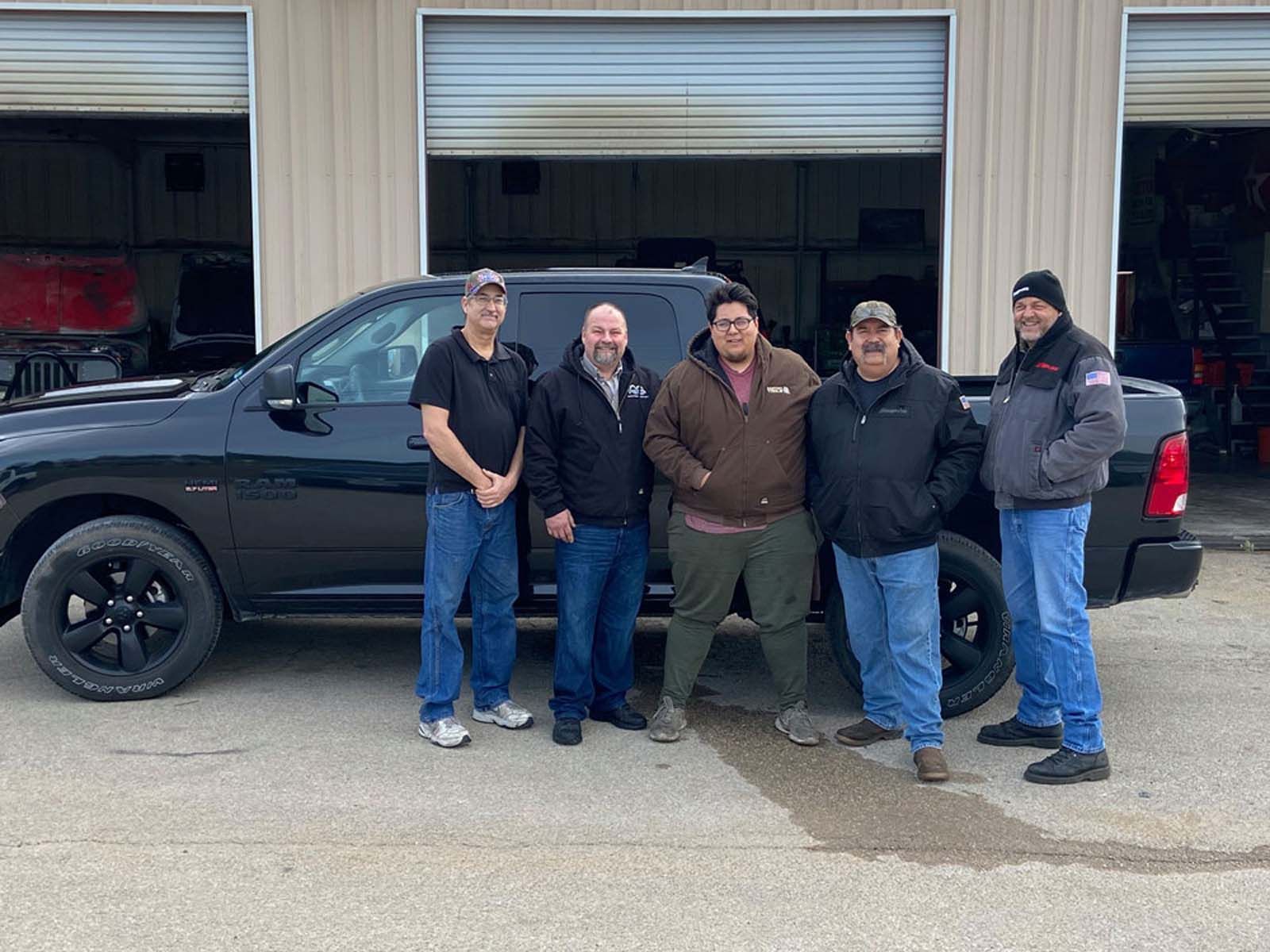 A group of men are posing for a picture in front of a truck.
