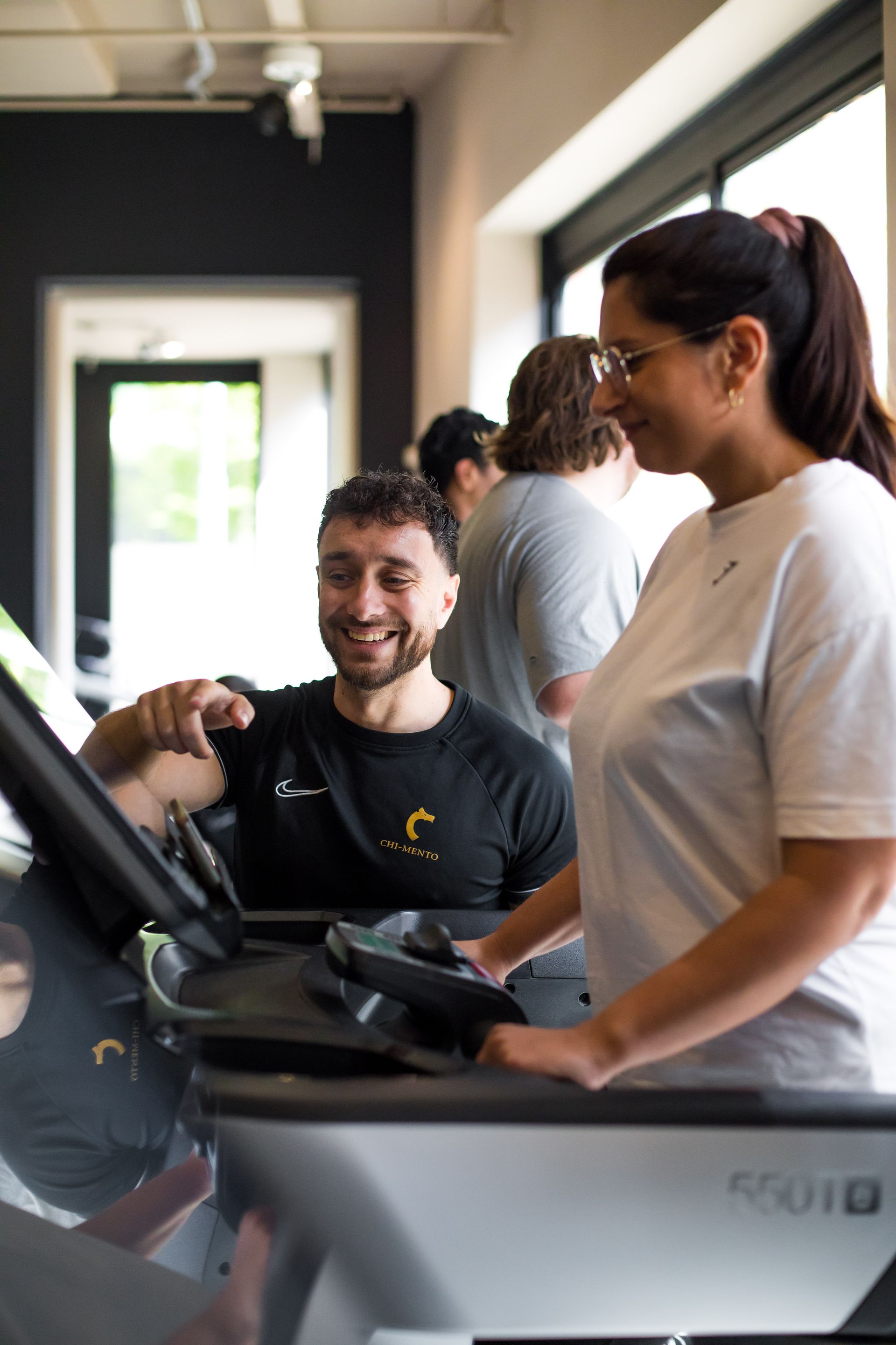 Een man en een vrouw staan naast elkaar op een loopband in een sportschool.